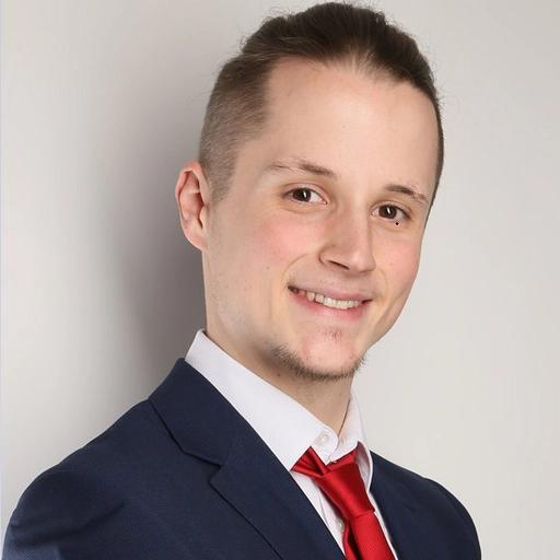 Portrait photo of a smiling man in a suit with a red tie