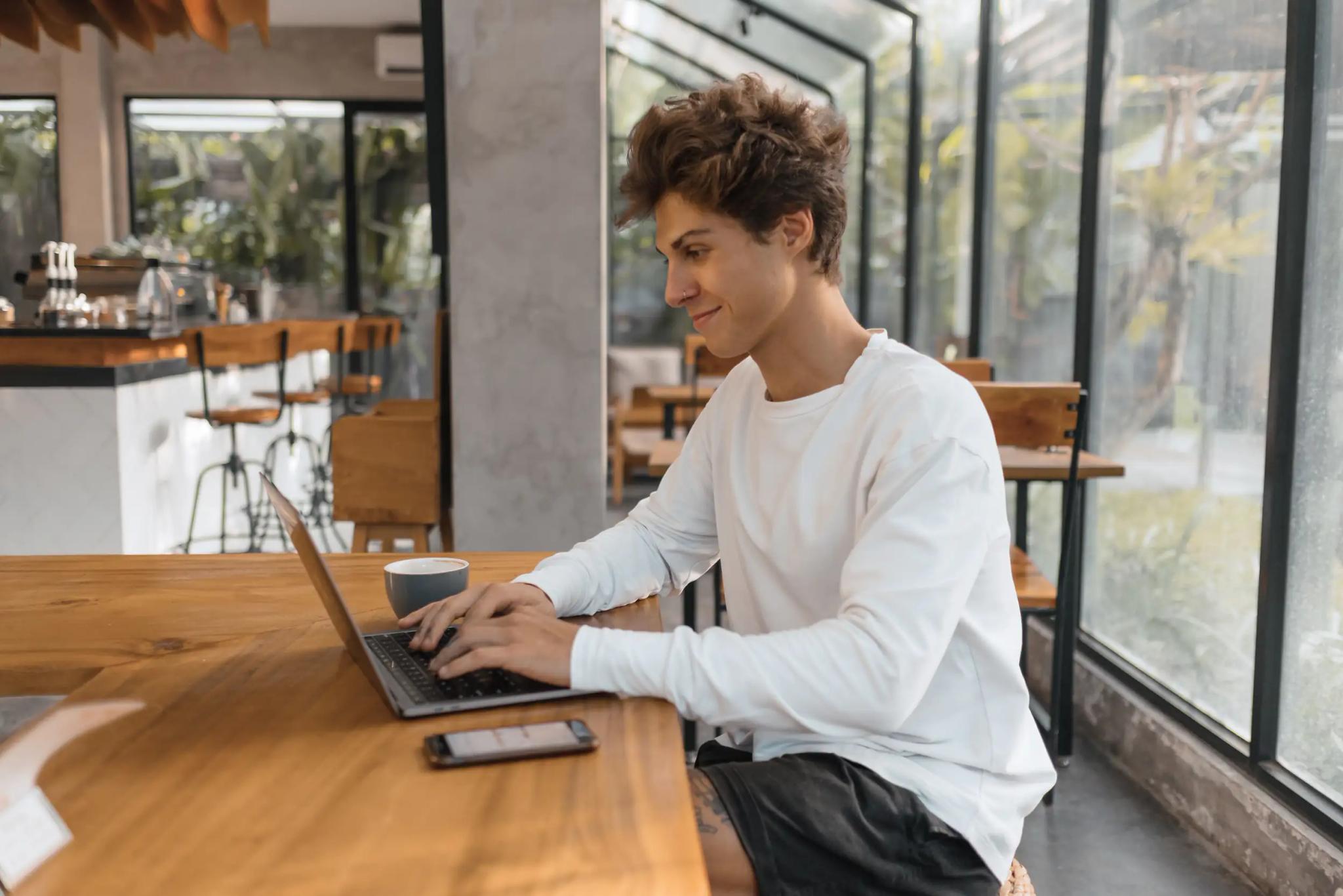 Young man working on a laptop in a café.