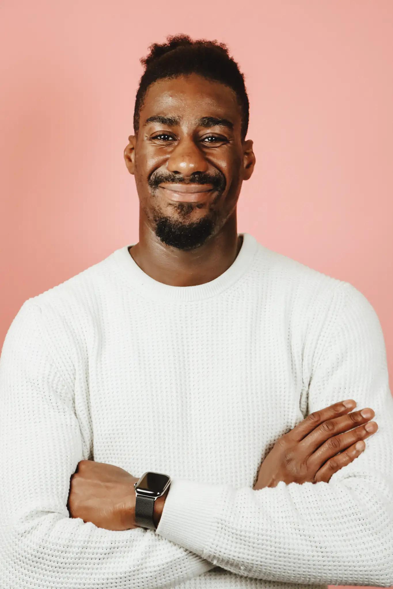 Smiling young man in white sweater against pink background
