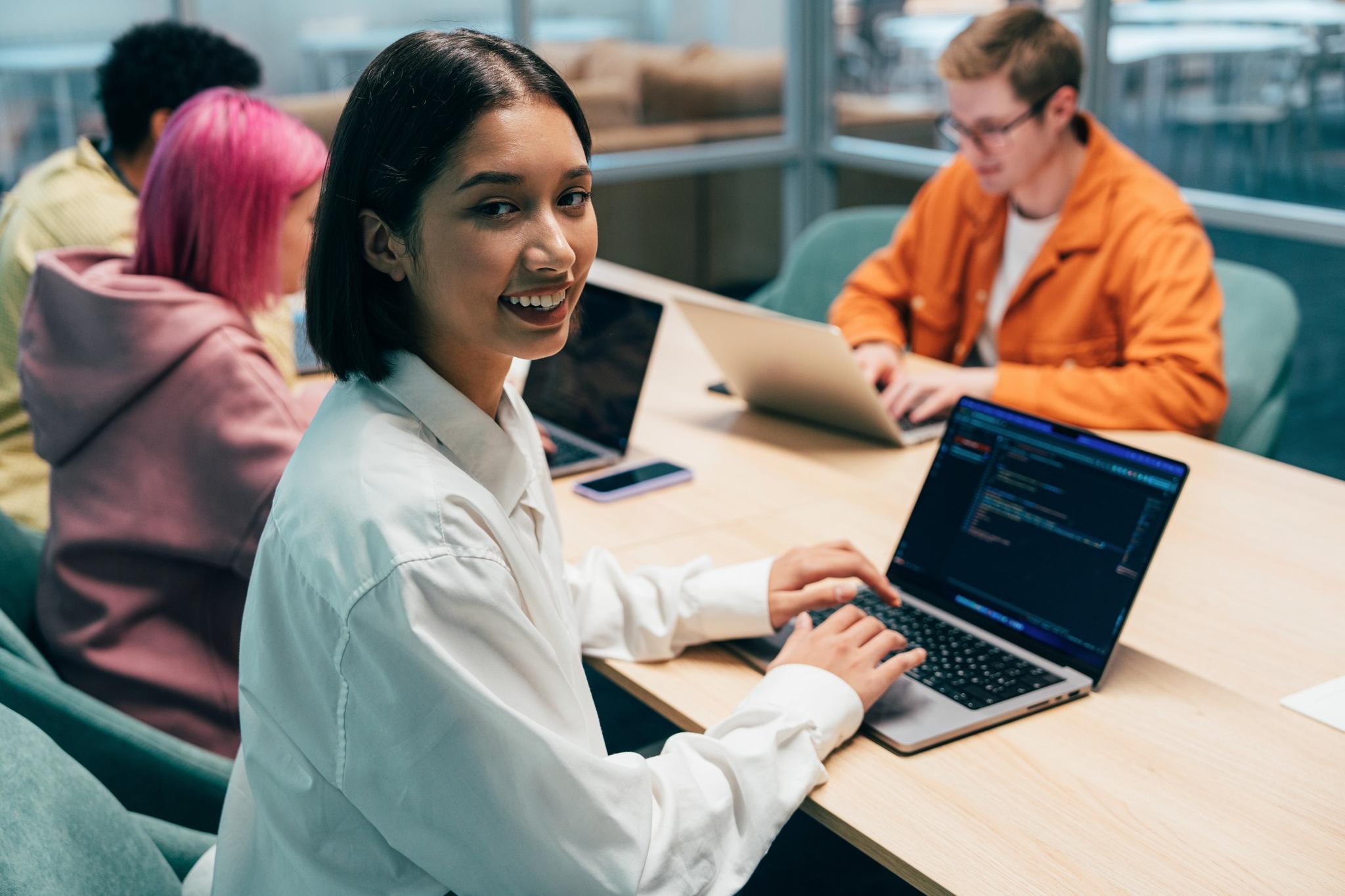 Junge Menschen, die zusammen an Laptops in einem modernen Büro arbeiten.
