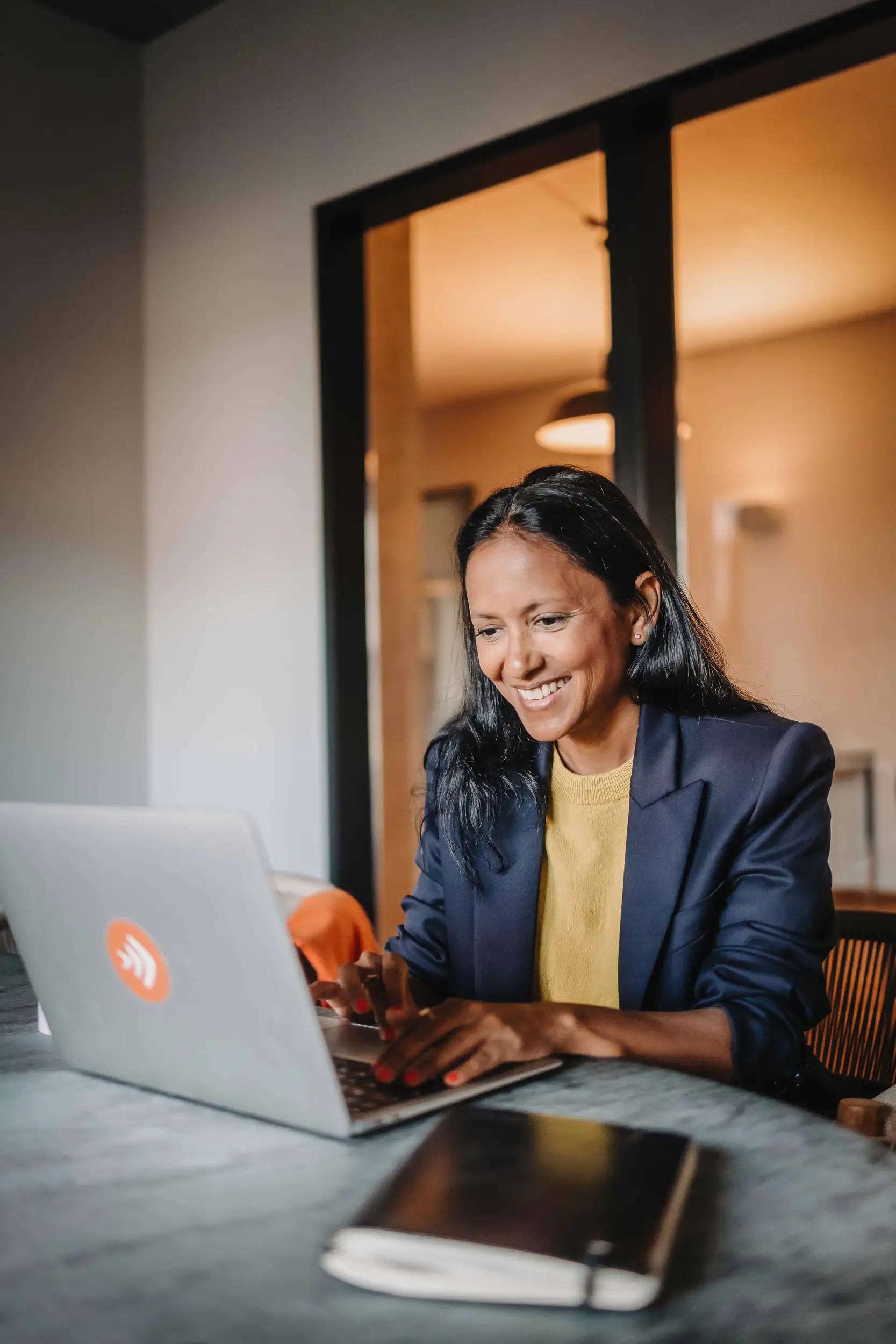 Smiling woman working on a laptop.
