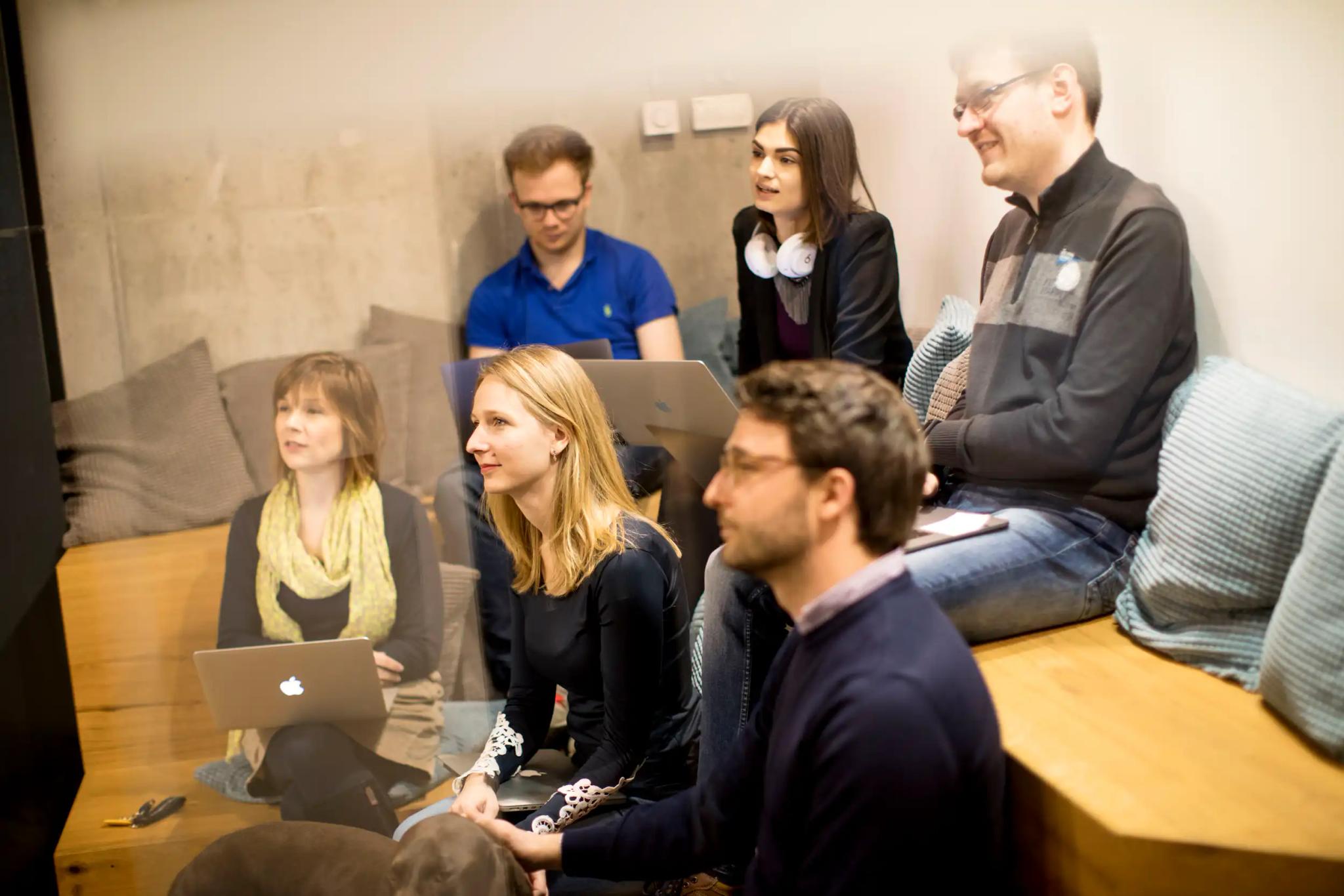 Group of people in an informal meeting with laptops.