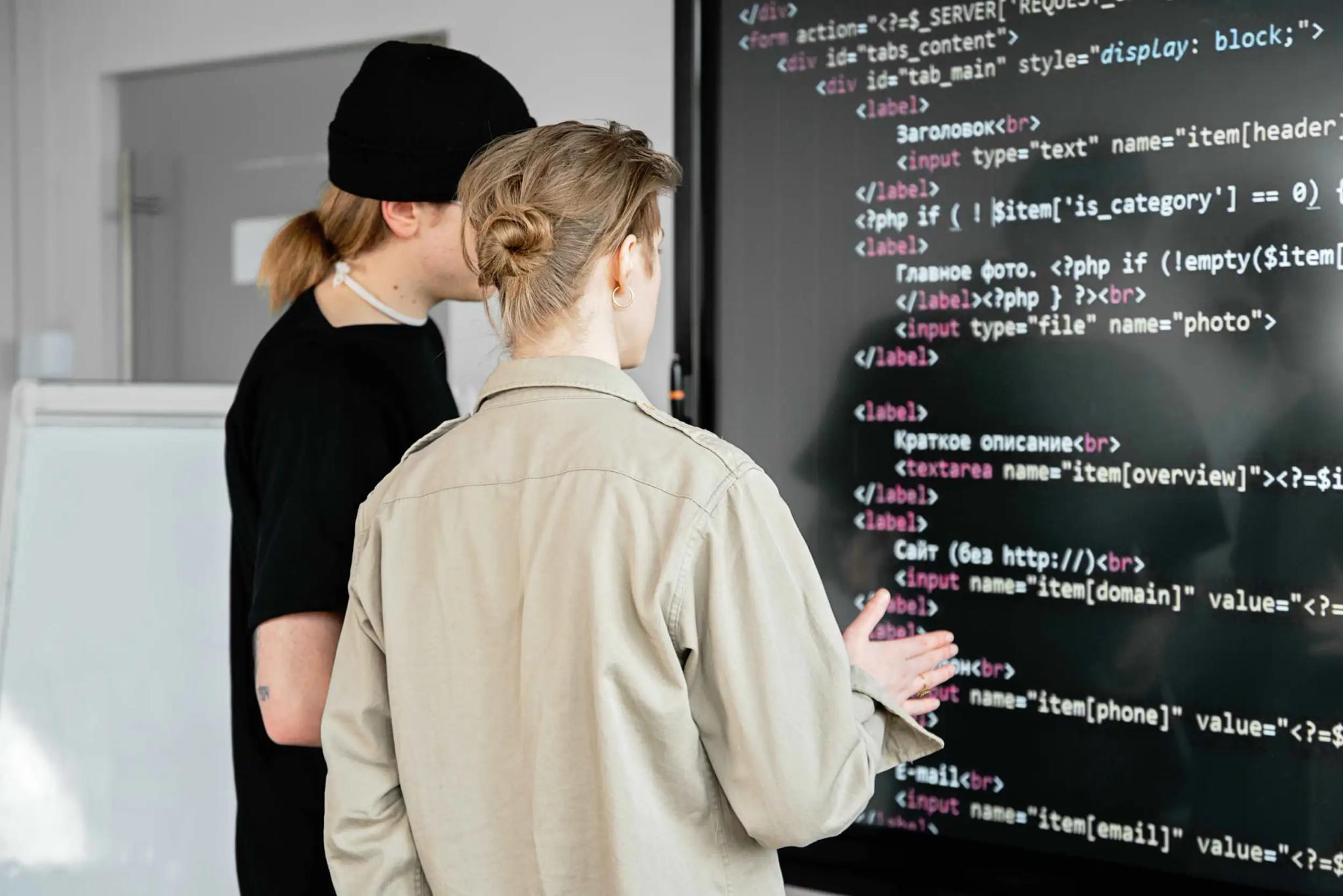 Two people looking at programming code on a screen together.