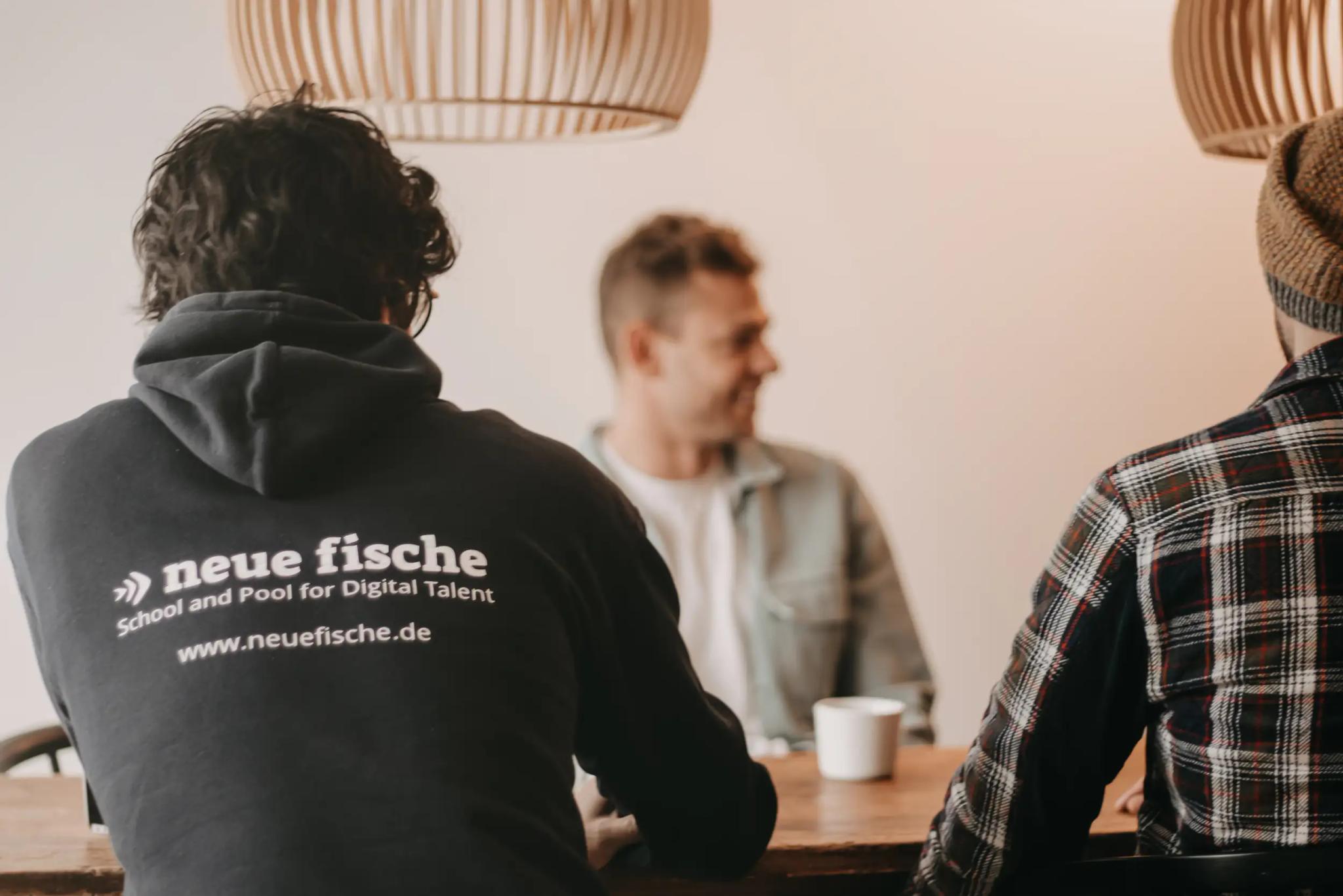 Three people sitting at a table having a conversation.