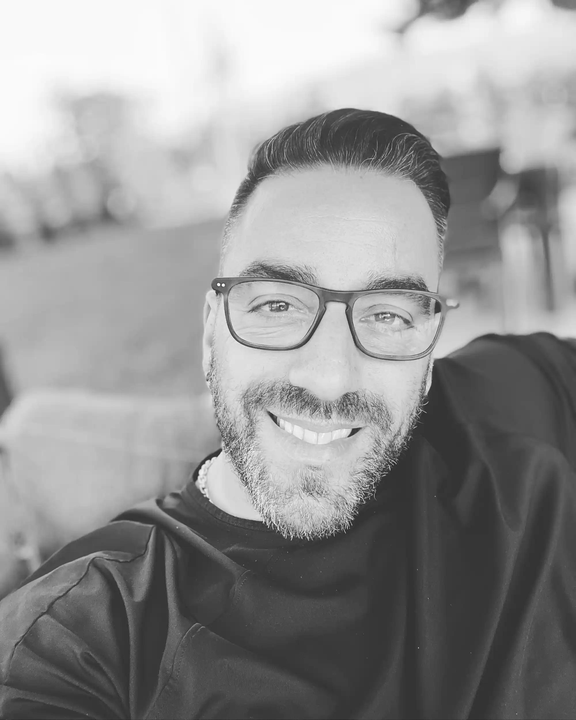 Smiling man with glasses taking a selfie.