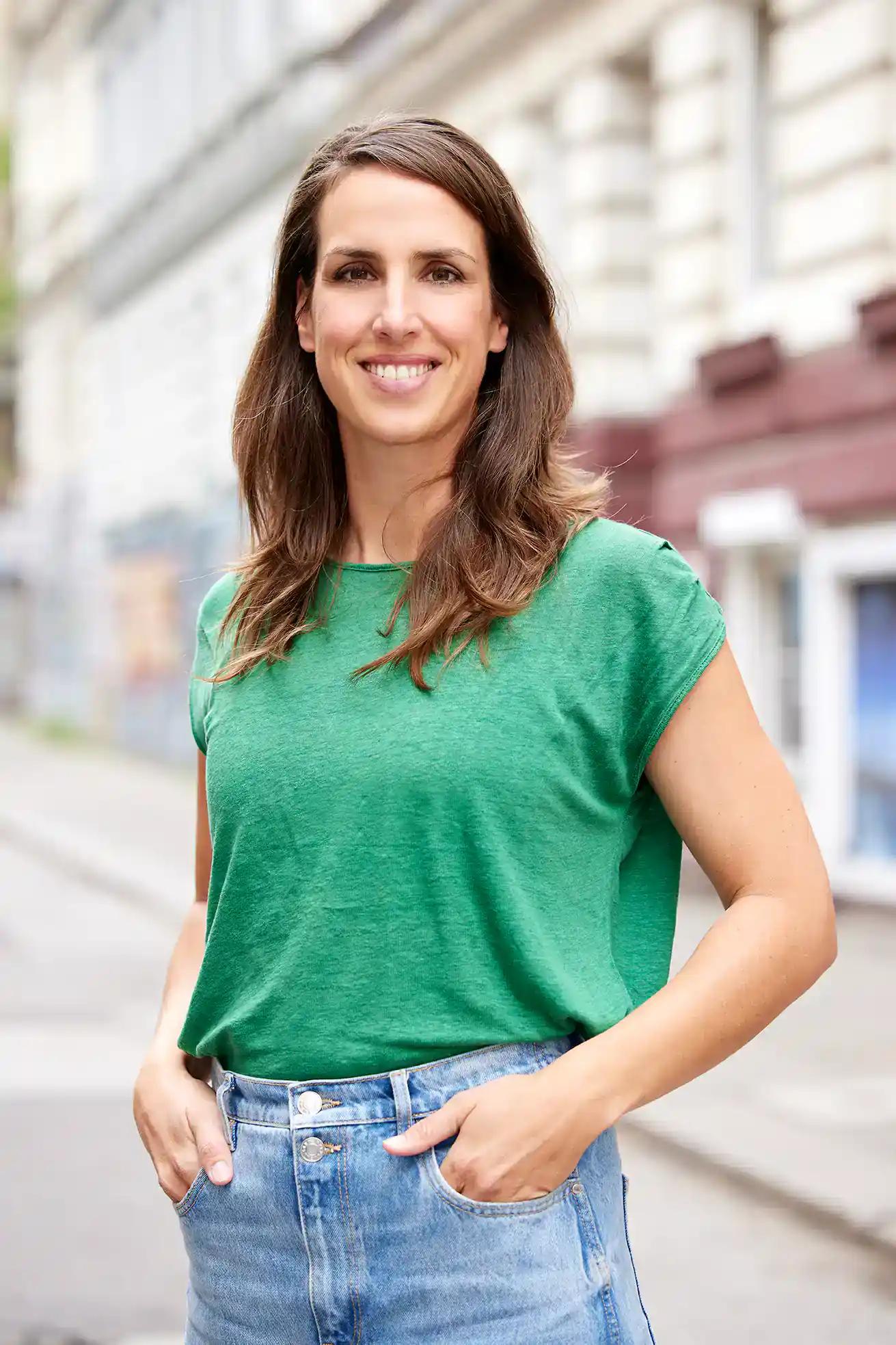 Woman smiling outdoors wearing green t-shirt and jeans