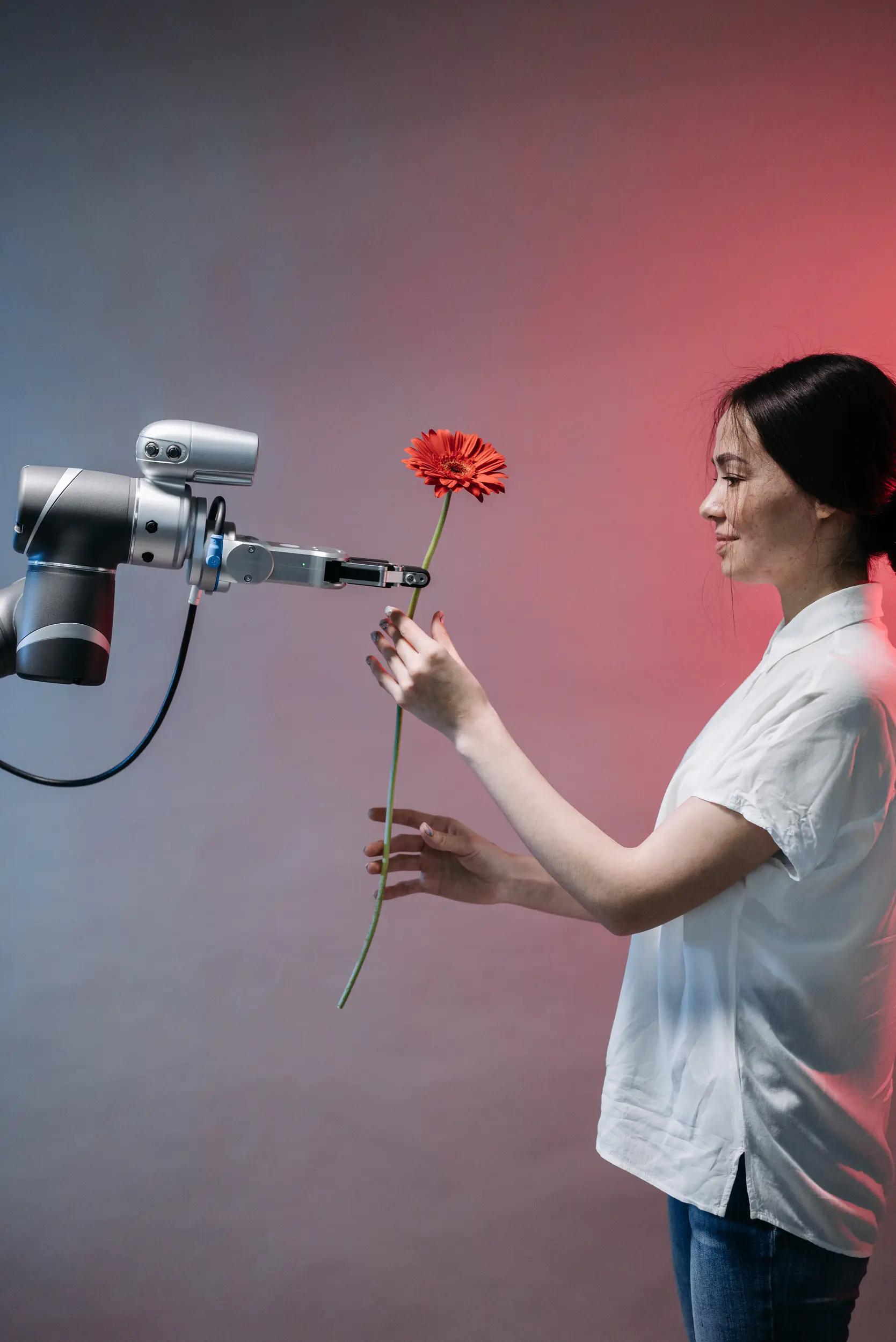 Roboterarm übergibt Frau eine Blume.