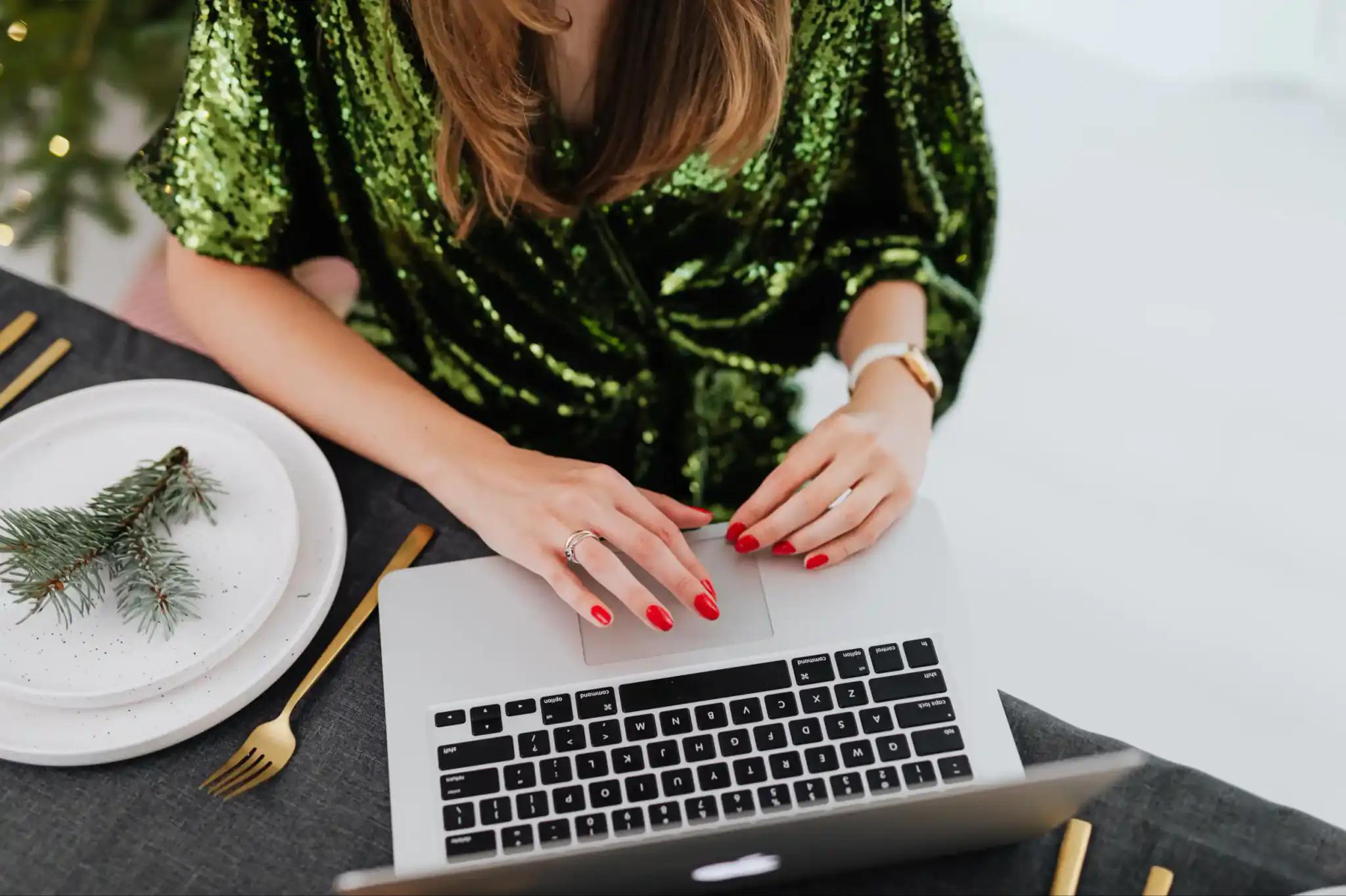 Woman in green blouse working on laptop at set table