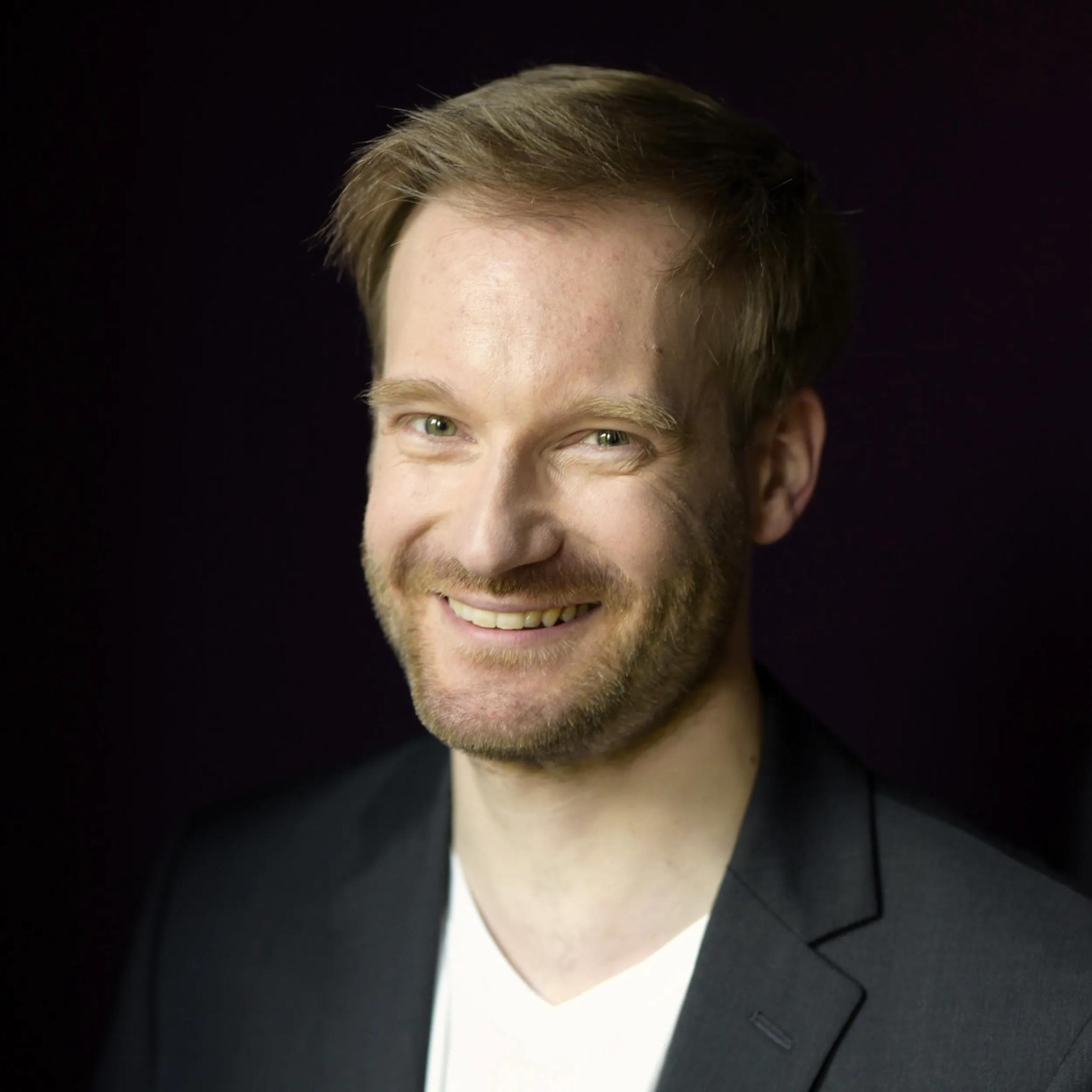 Porträt eines lächelnden Mannes vor dunklem Hintergrund