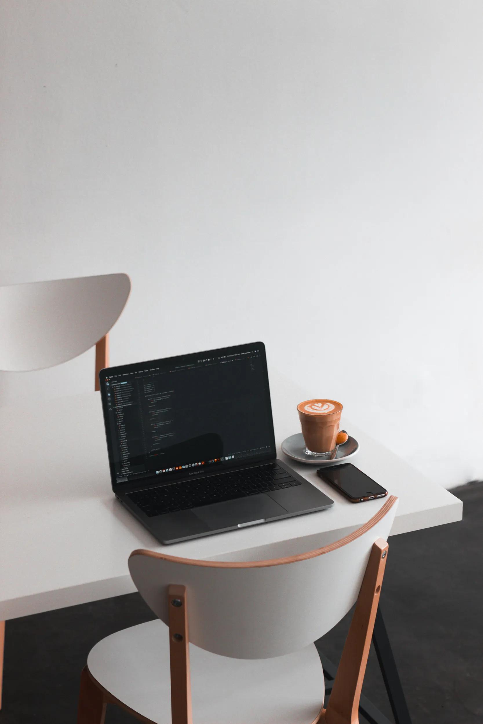 Laptop, smartphone, and coffee on a white table
