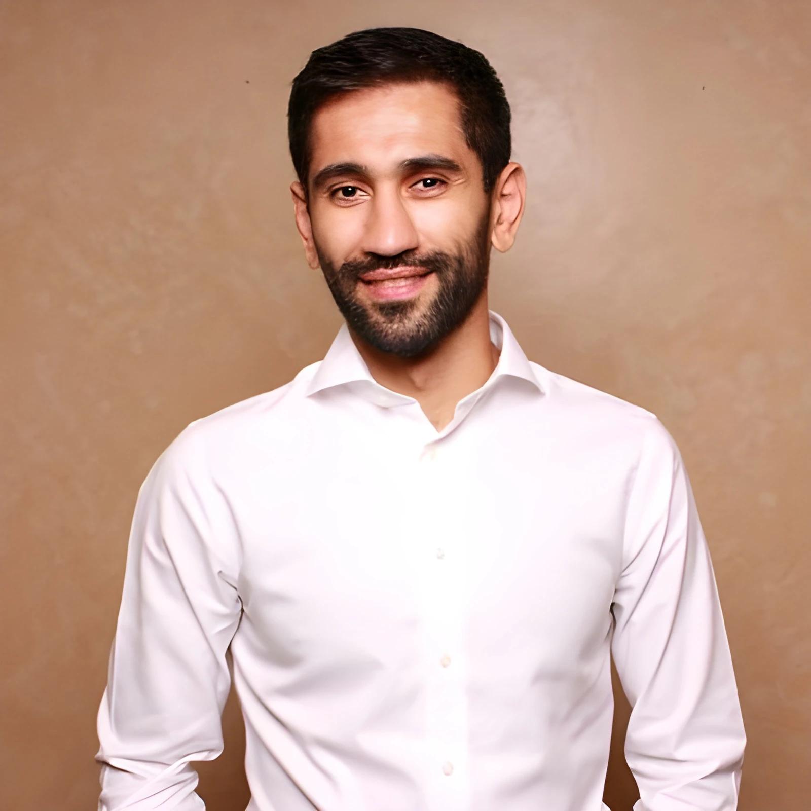 Portrait of a smiling man in a white shirt against a beige background.