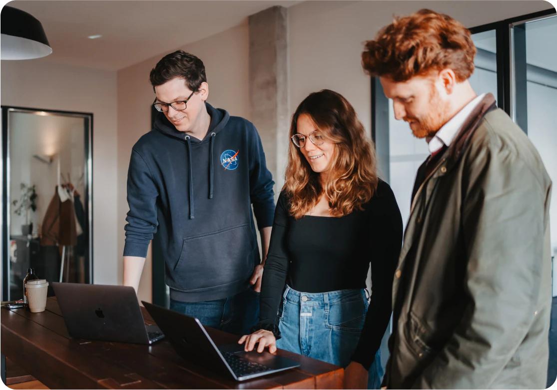 Three people working together on laptops in an office.