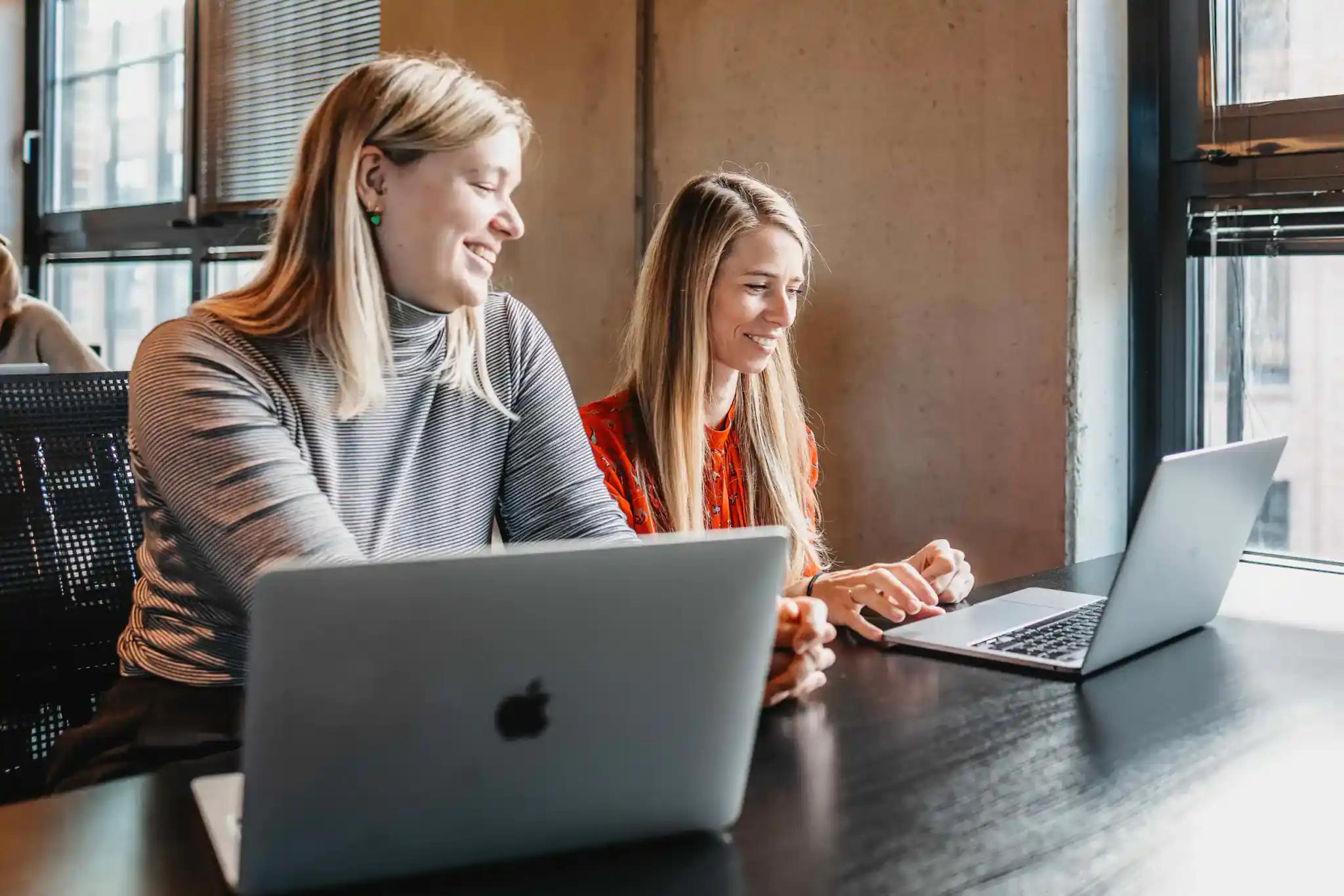 Two women working together on laptops