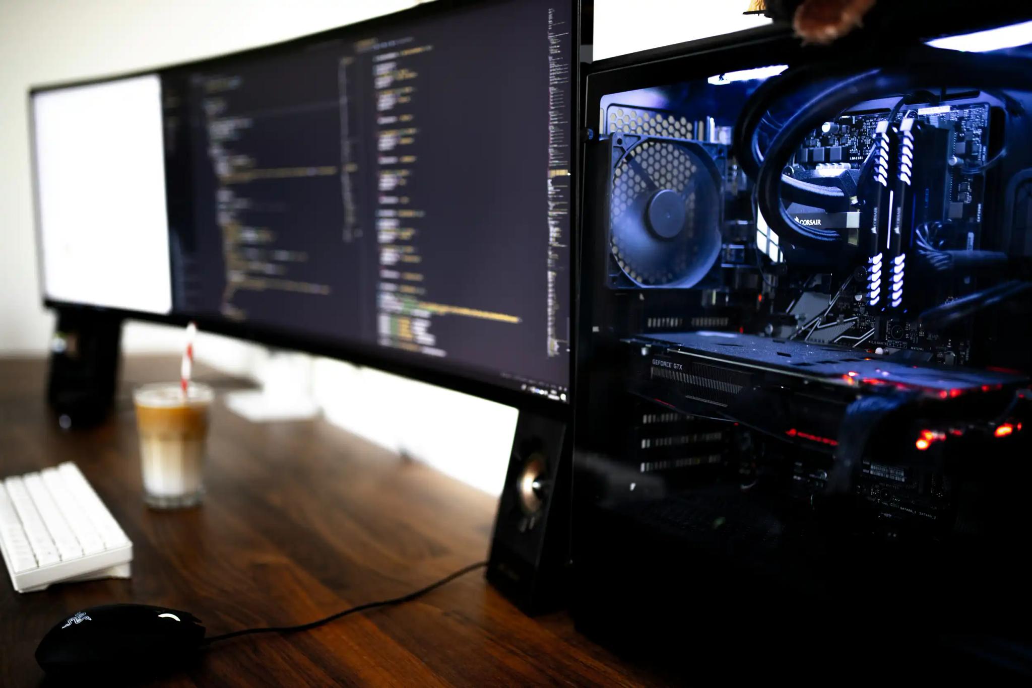 Arbeitsplatz mit großem Monitor und offenem PC-Gehäuse