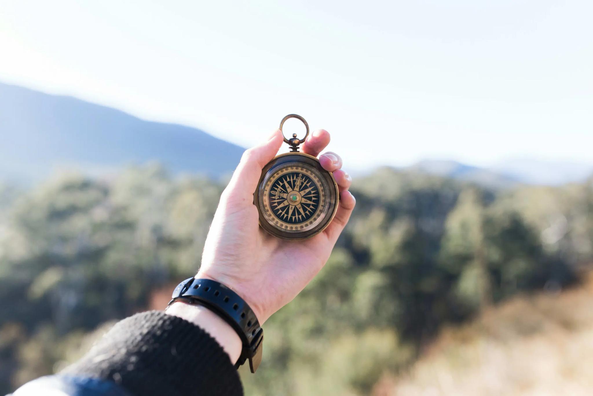 Hand holding a compass against a landscape