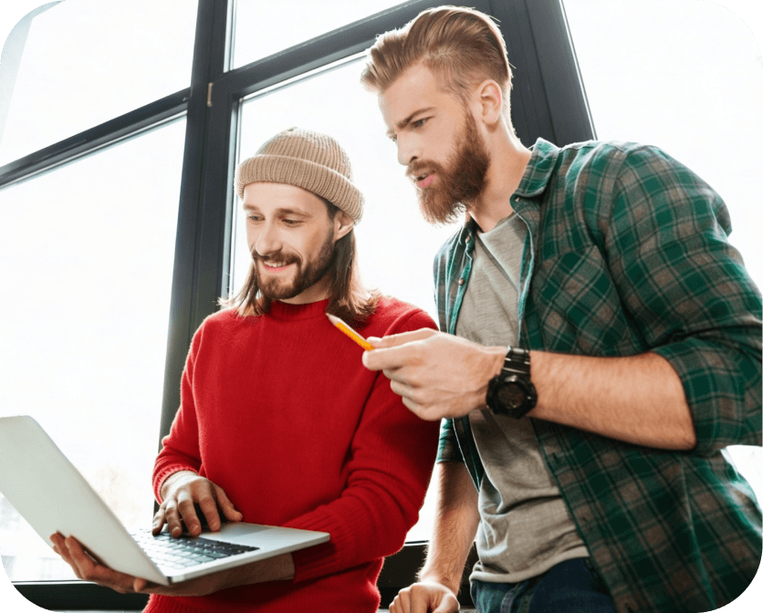 Two men working together on a laptop.