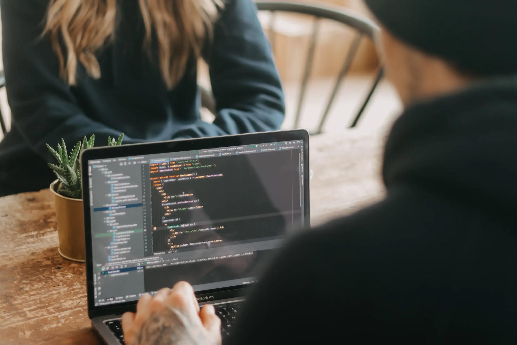 Person working on a laptop with programming code.