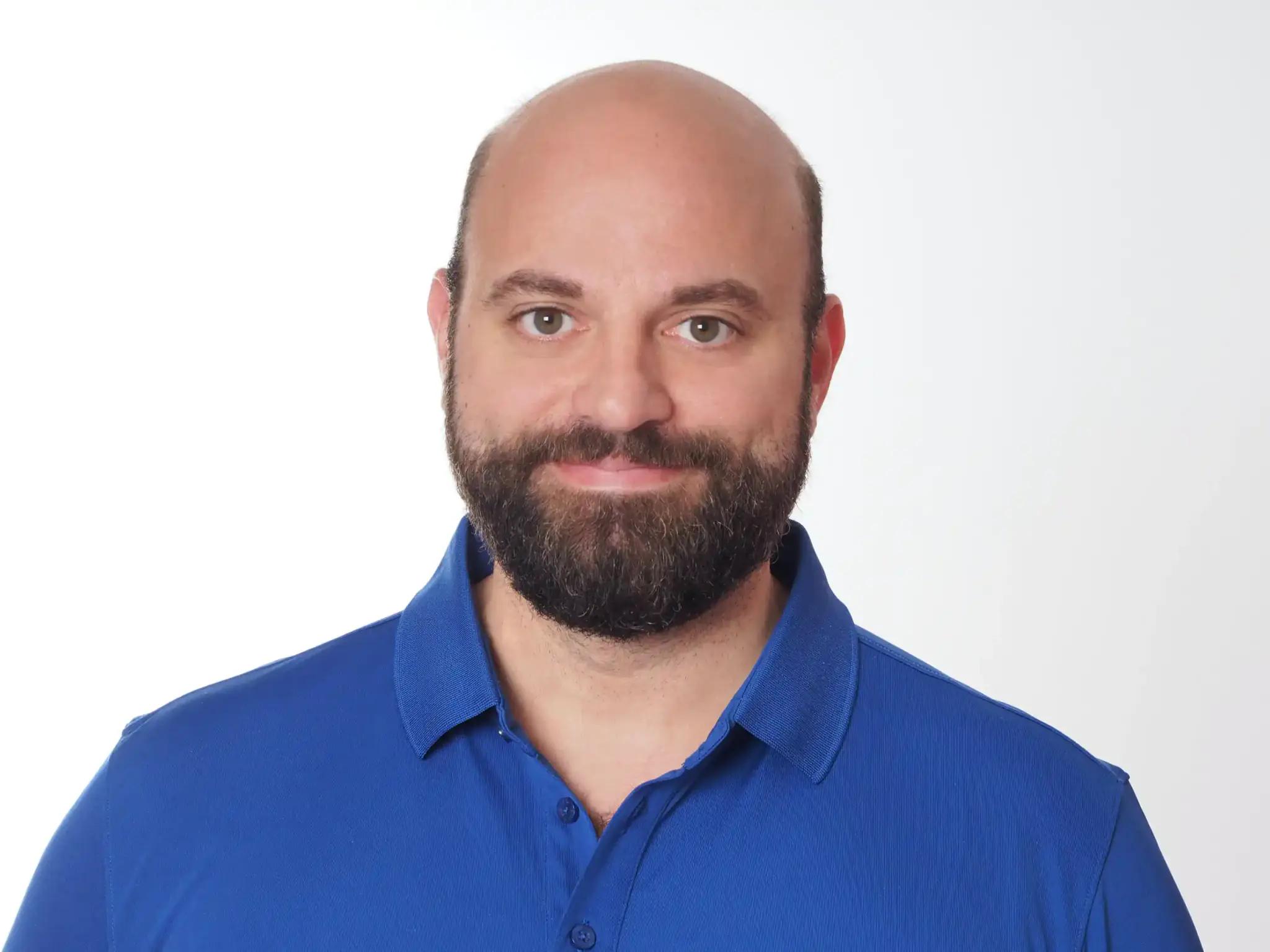 Portrait of a bearded man in a blue shirt against a white background