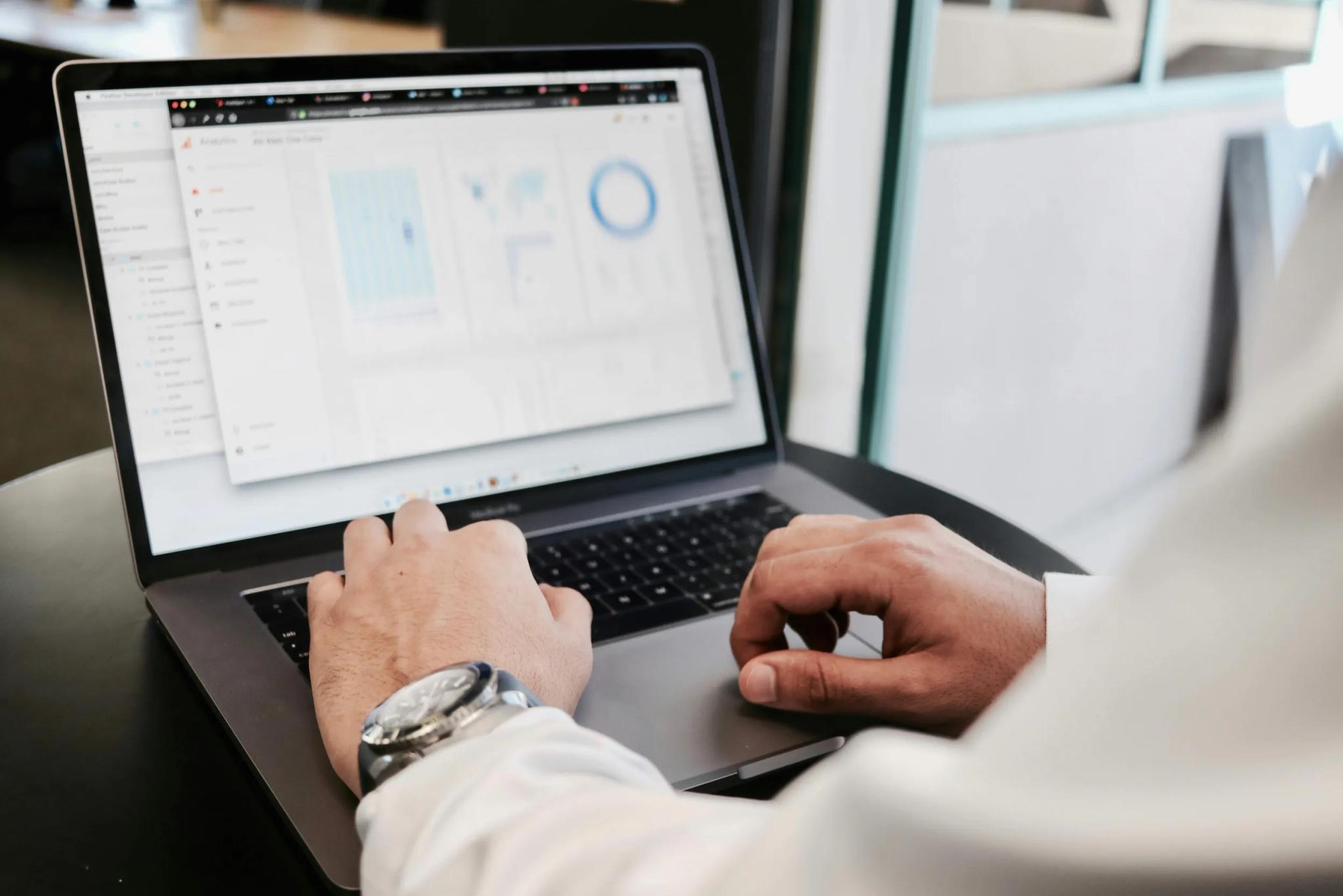 Person arbeitet an einem Laptop mit Diagrammen auf dem Bildschirm.