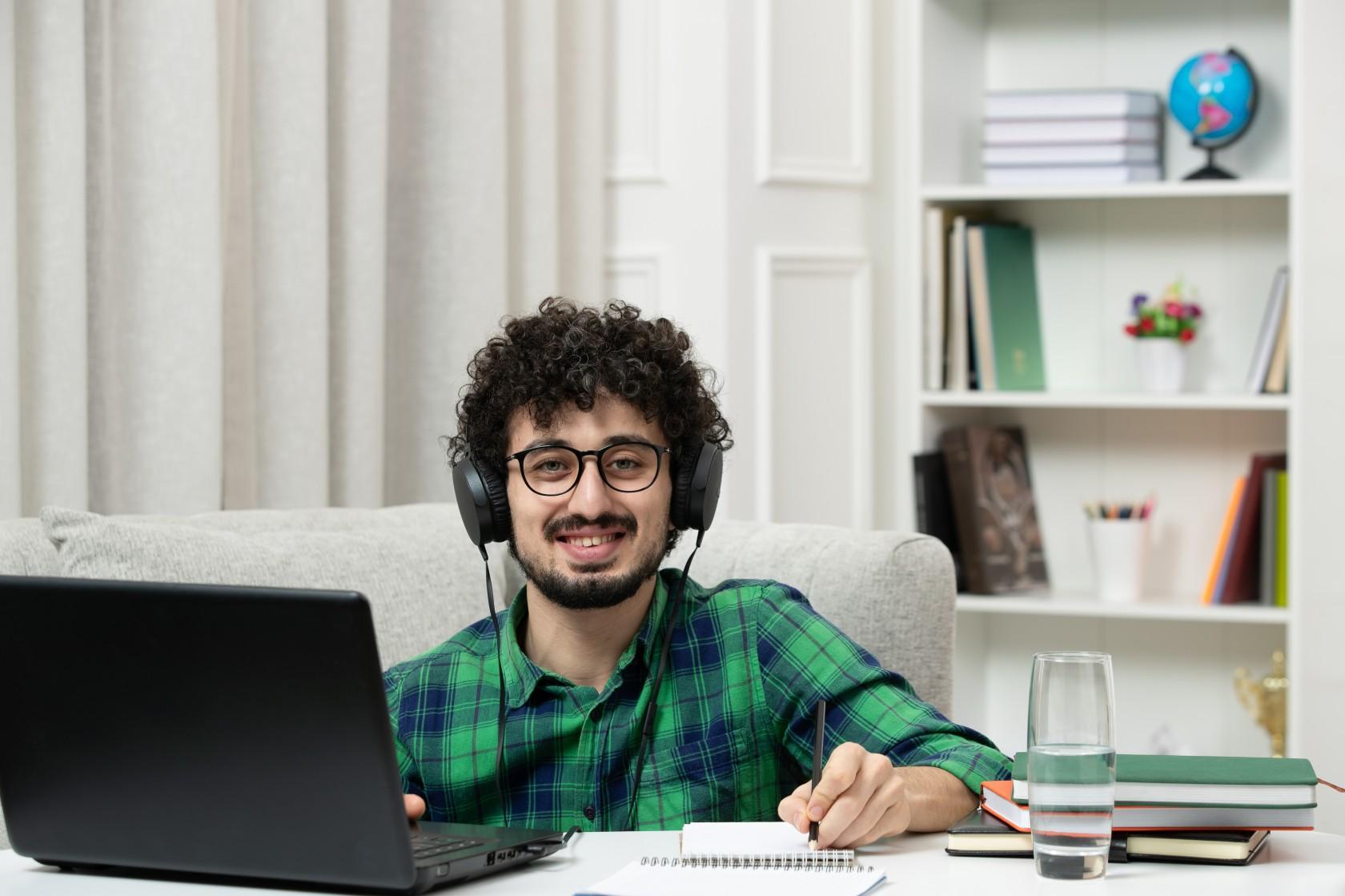 Junger Mann mit Kopfhörern arbeitet am Laptop.
