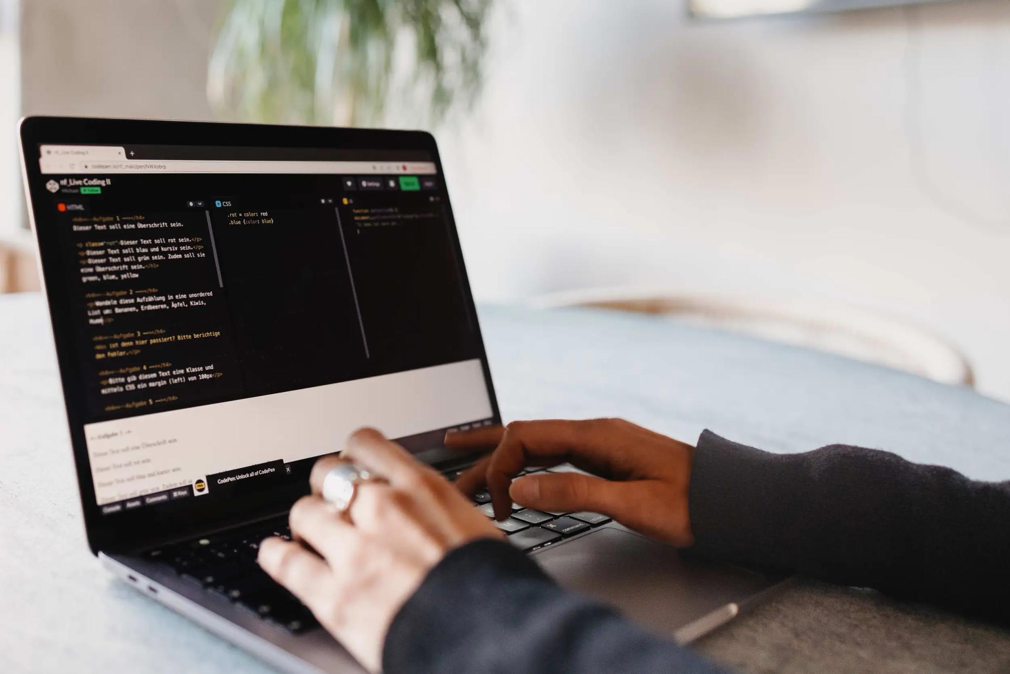 Person typing on laptop with code on screen