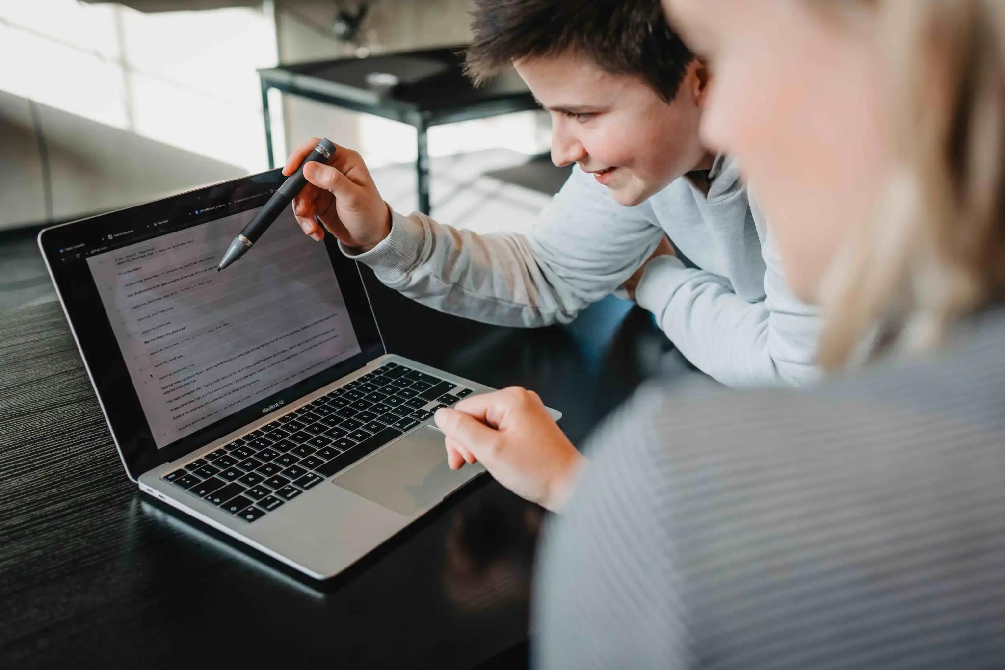Two people working on a laptop screen.