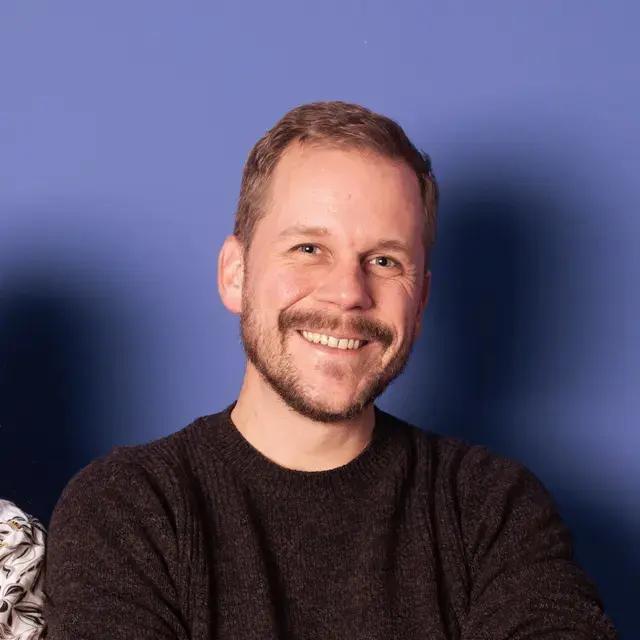 Lächelnder Mann vor blauem Hintergrund.