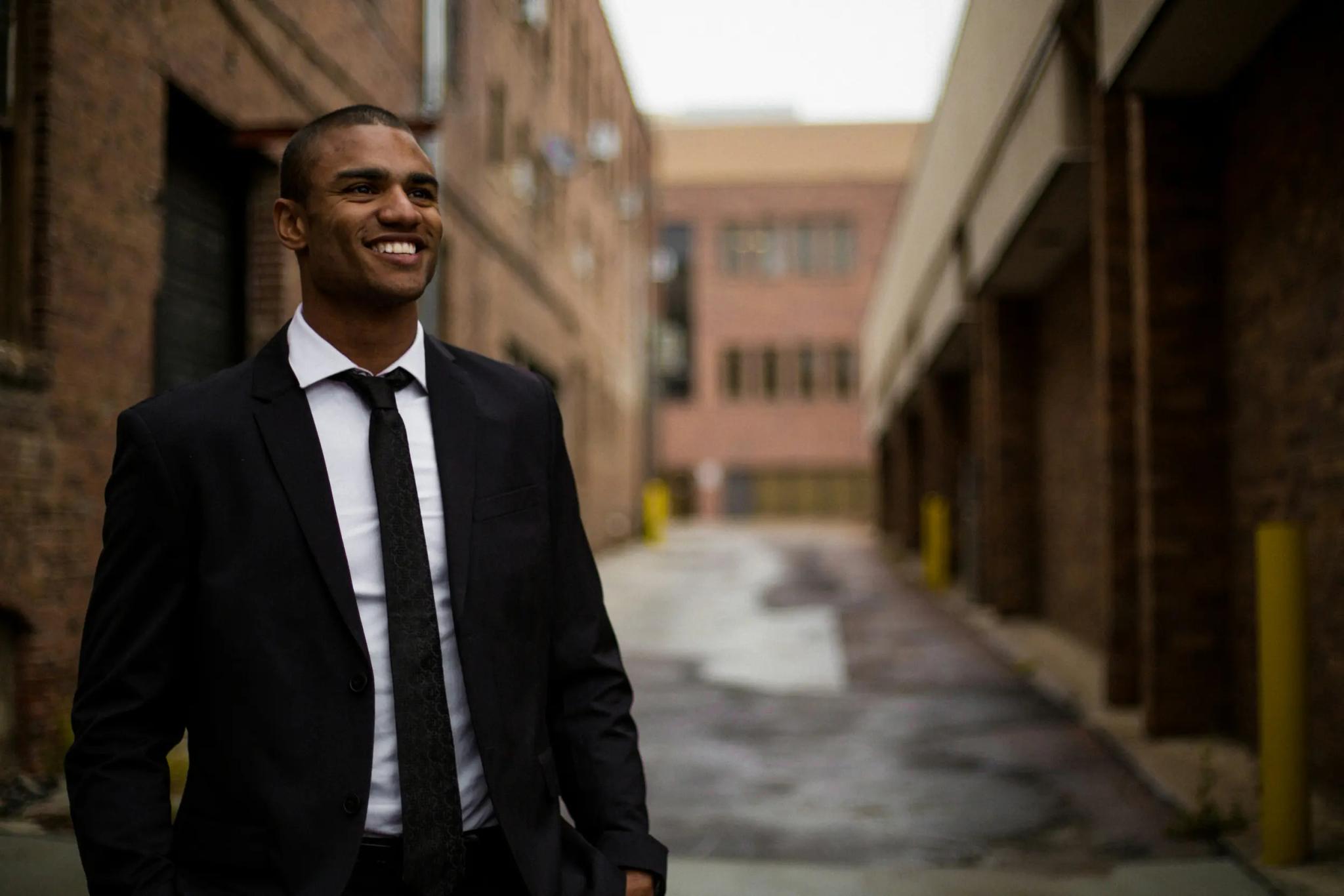 Smiling man in suit in an urban alley.