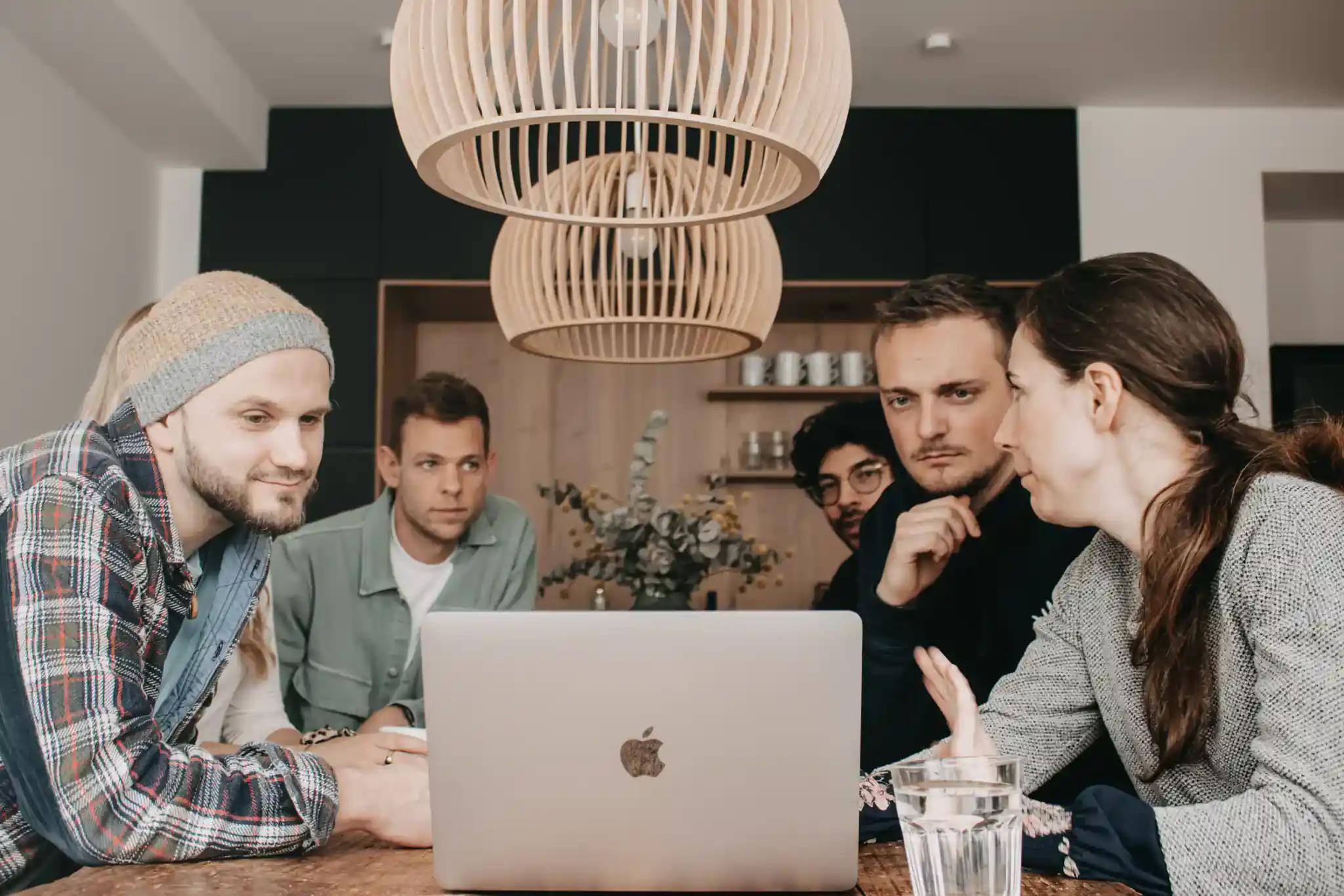Group of people working at a table with a laptop