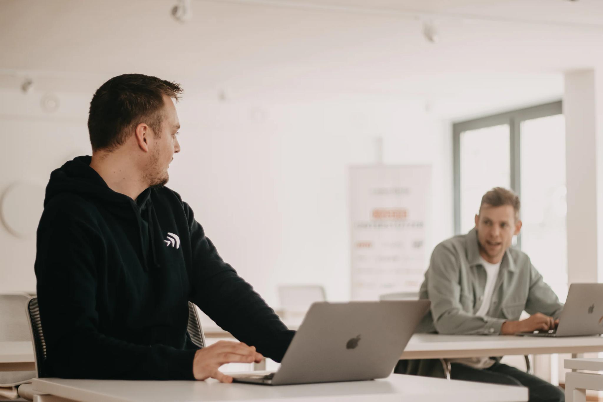 Two men working with laptops in a modern office.