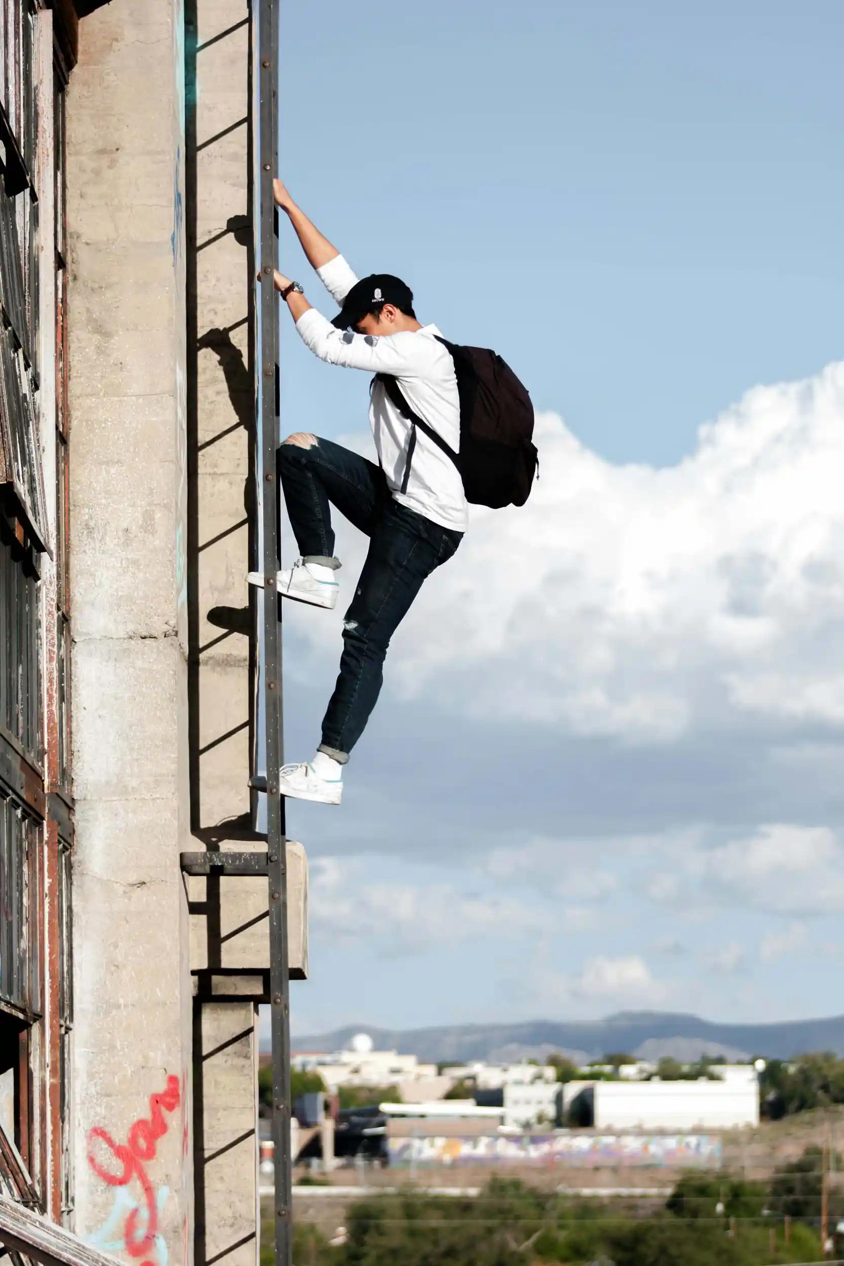 Person klettert Leiter an Gebäudewand hoch