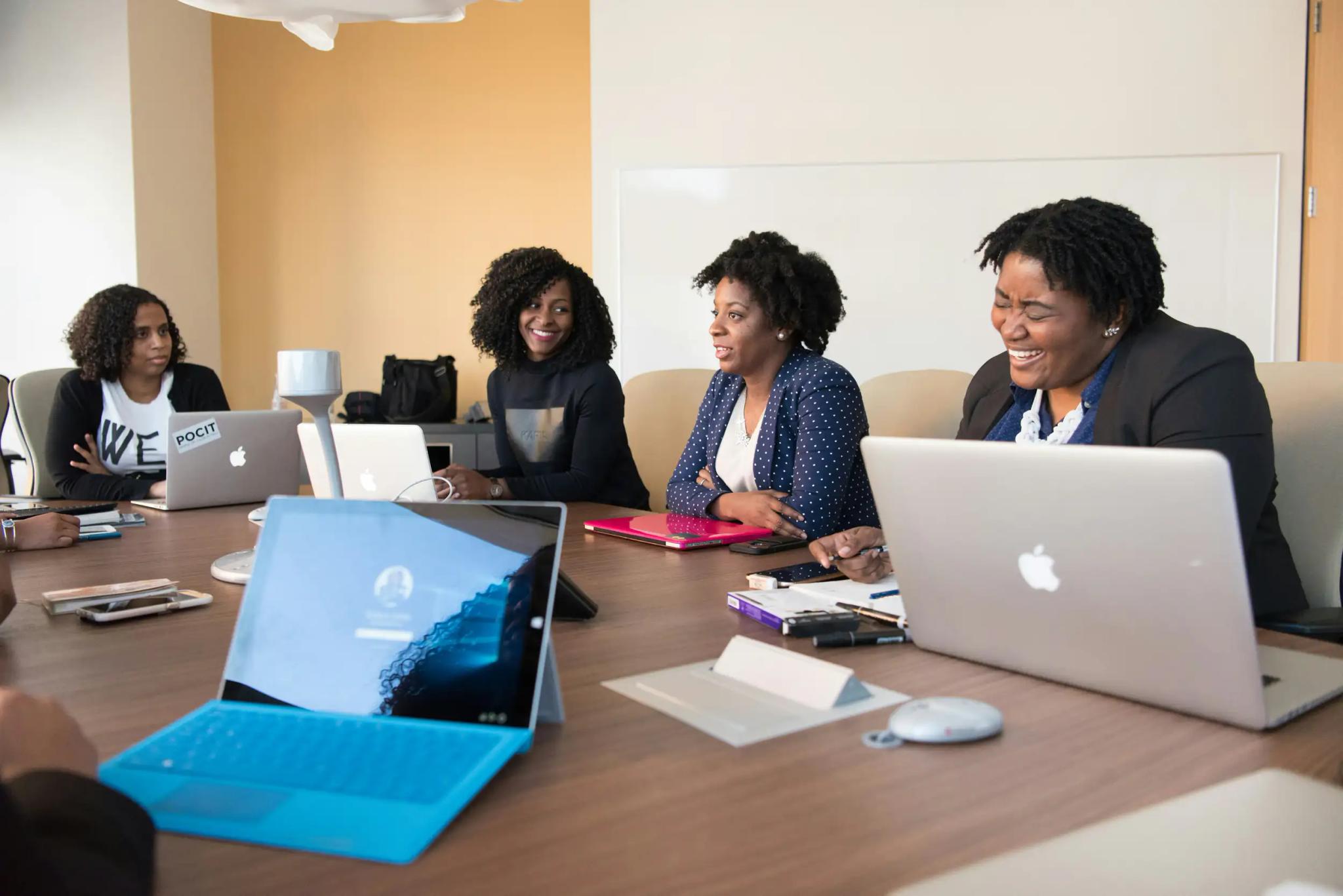 Frauen in einer Besprechung mit Laptops an einem Konferenztisch.