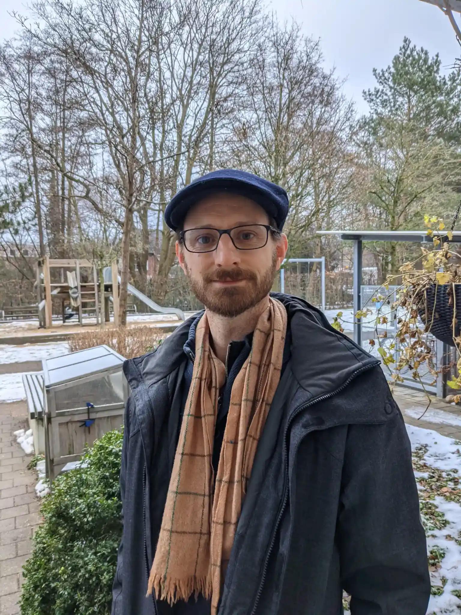 Man with glasses, cap, and scarf outdoors in winter