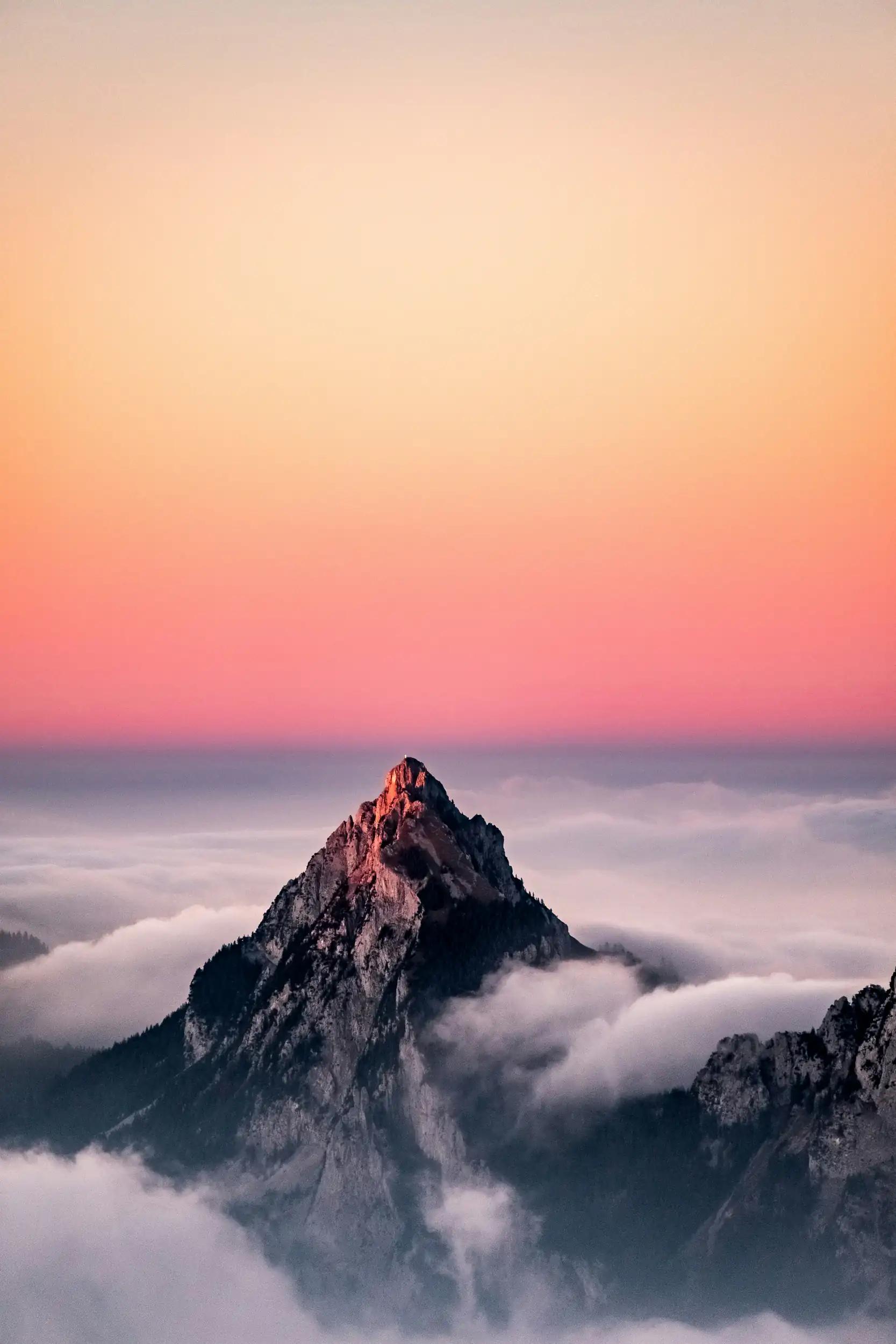 Mountain peak above clouds at sunset
