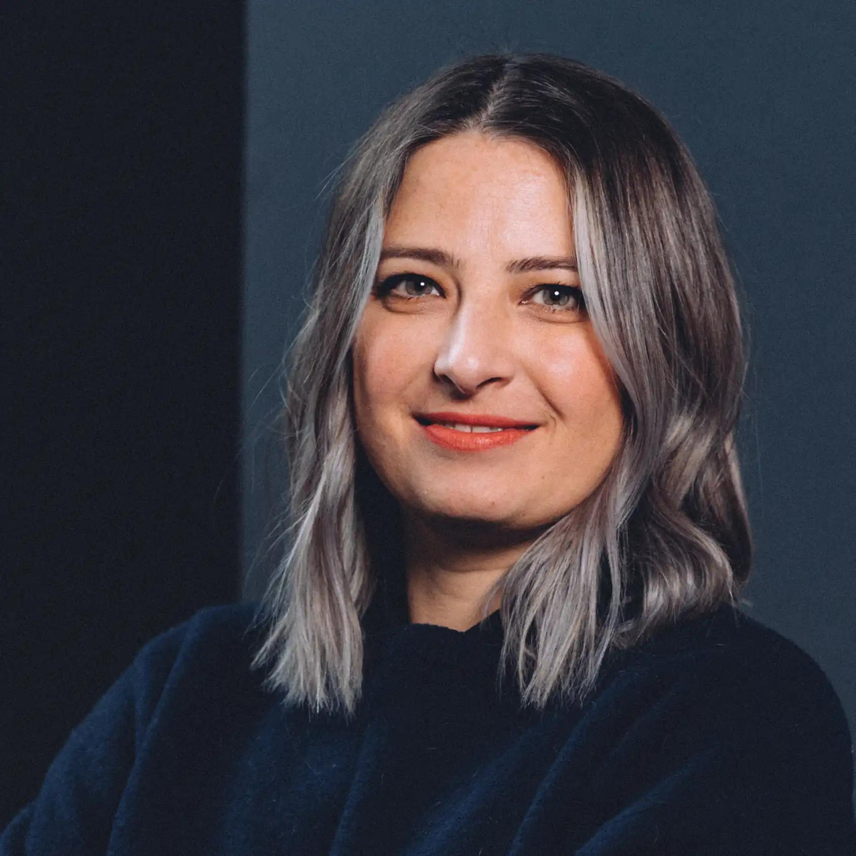 Portrait of a smiling woman with medium-length gray hair.