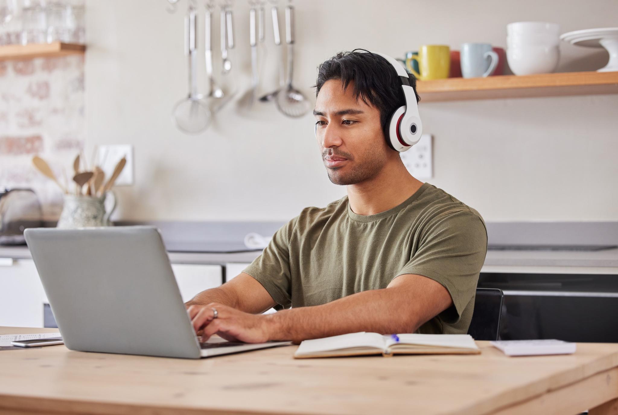 Mann mit Kopfhörern arbeitet am Laptop