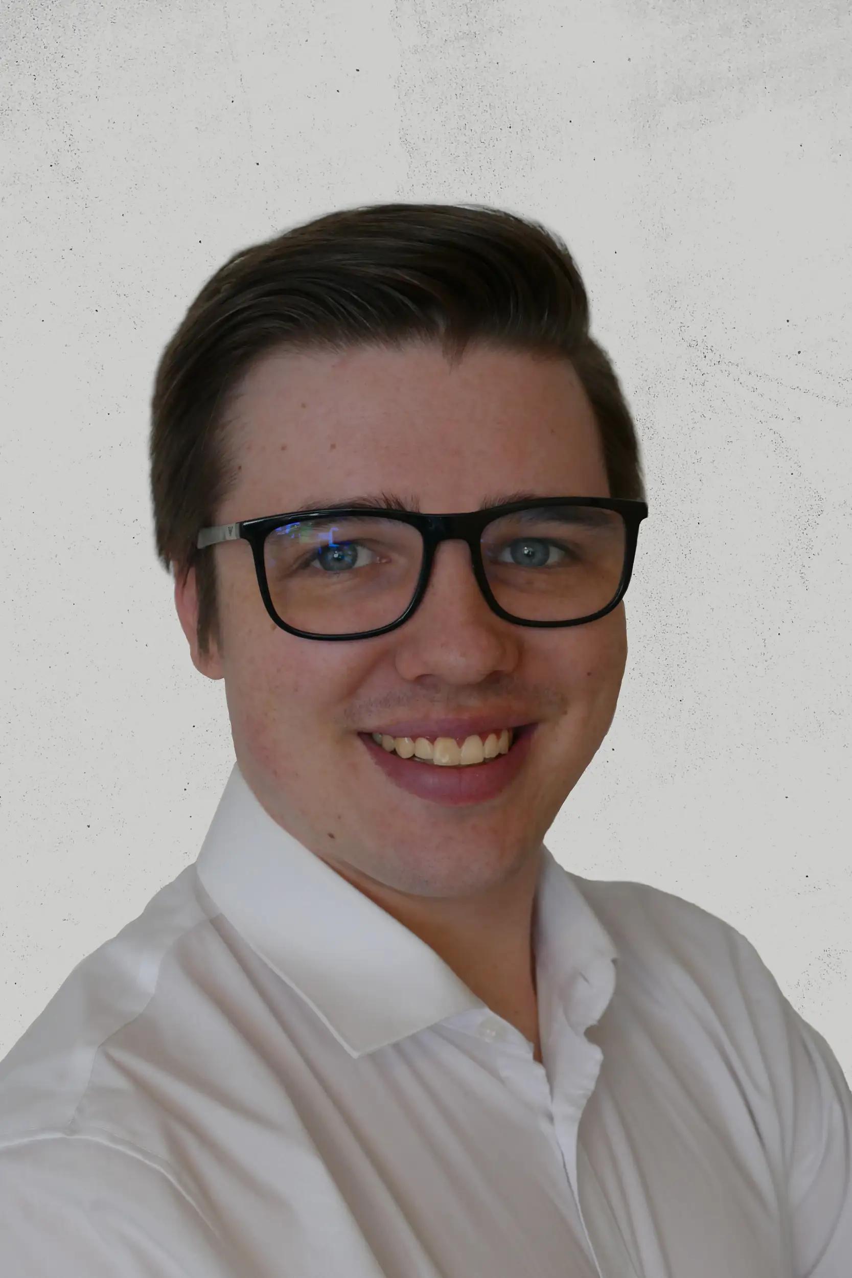 Portrait of a smiling man wearing glasses and a white shirt.