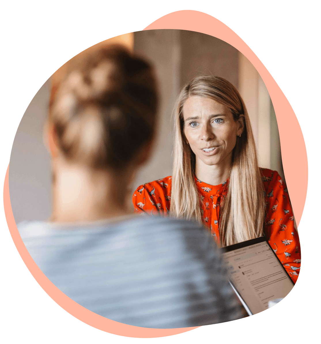 Two women in conversation, one with a laptop