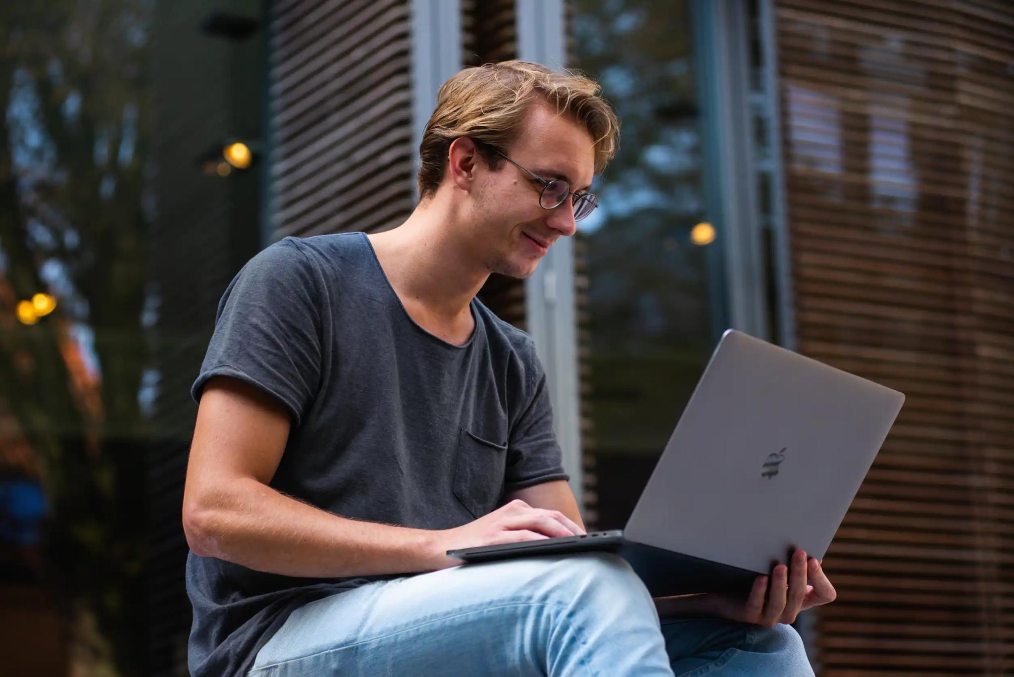 Young man working on a laptop outdoors.