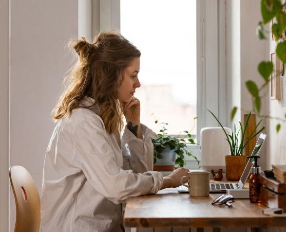 Frau arbeitet am Laptop mit Kaffeetasse