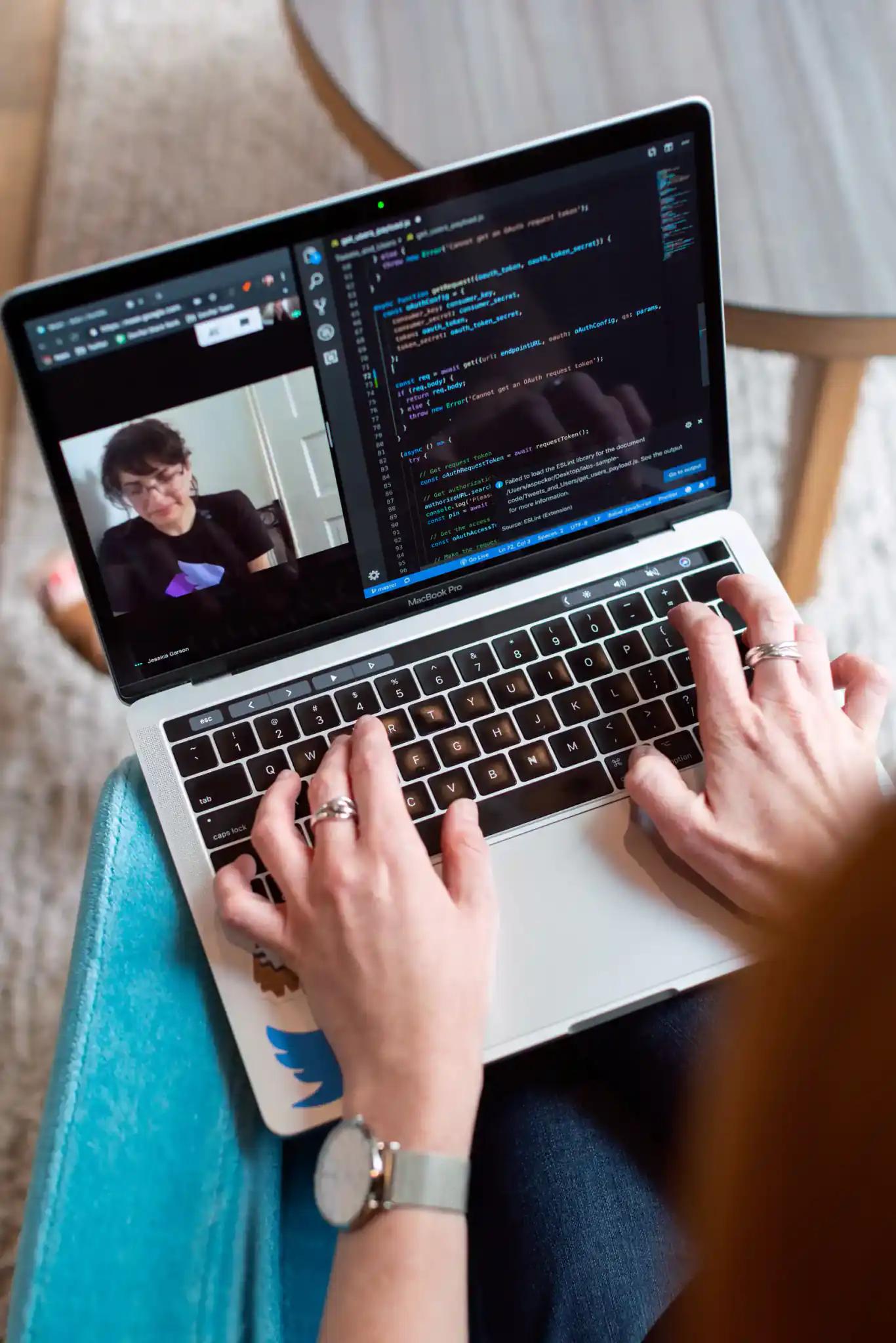 Laptop with video call and programming code on screen.
