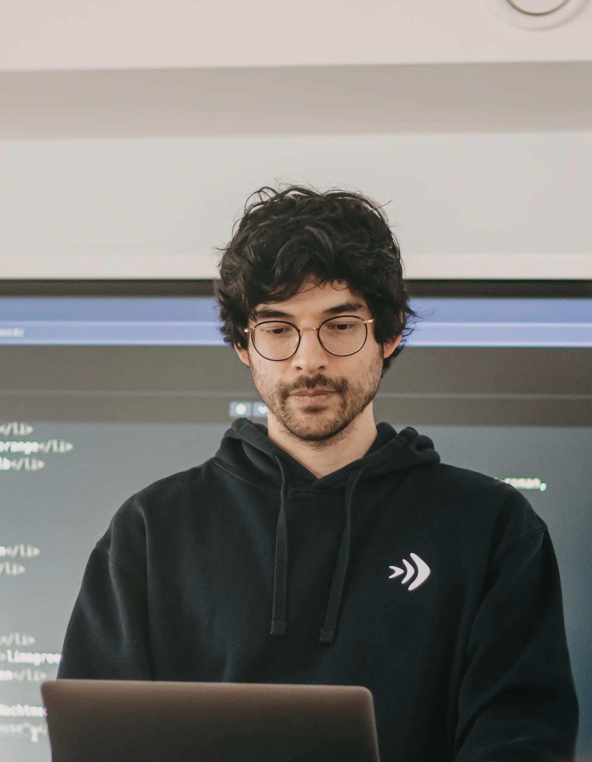 Mann mit Brille arbeitet vor einem Laptop.