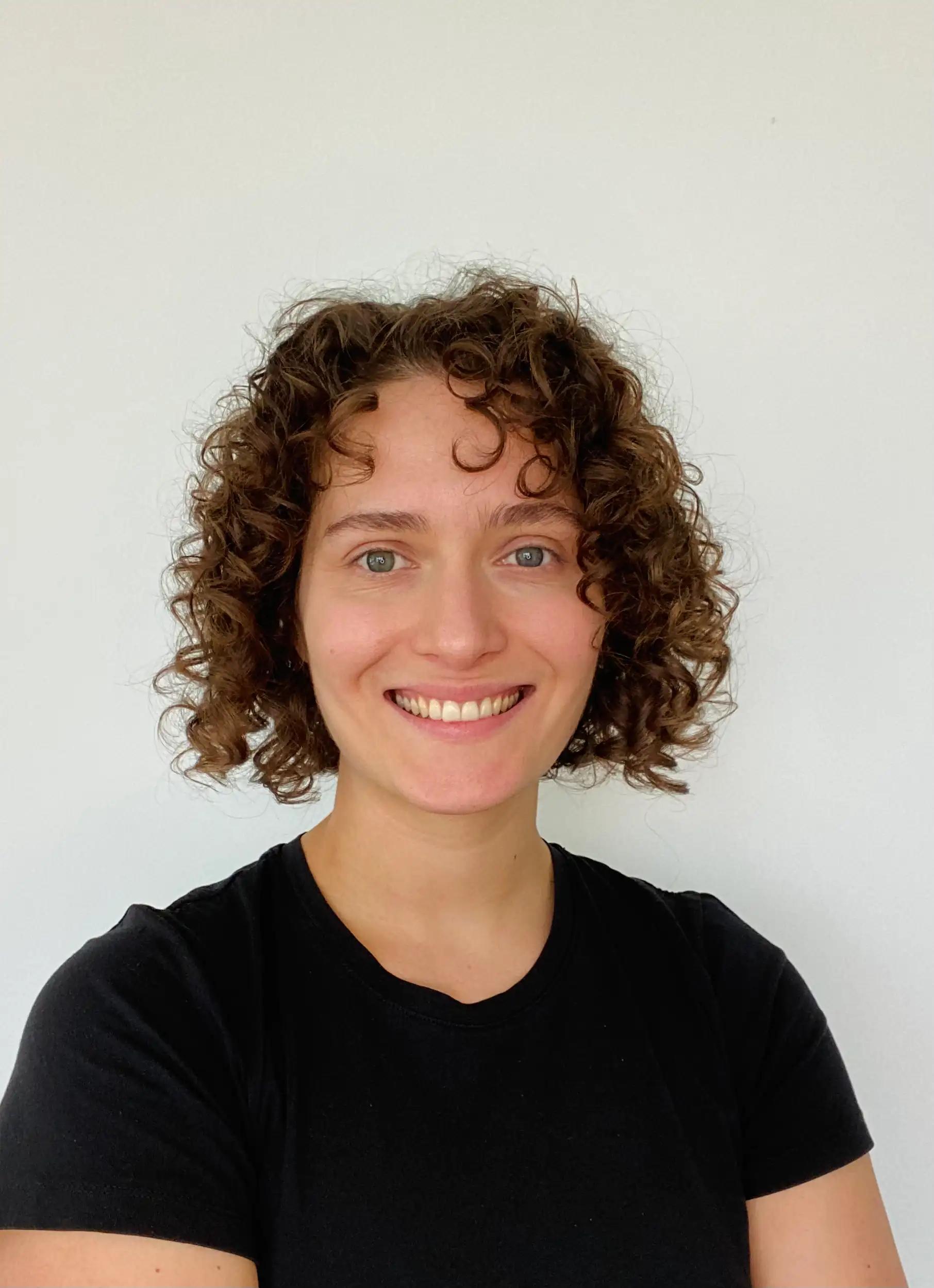 Portrait of a smiling woman with curly hair against a white background