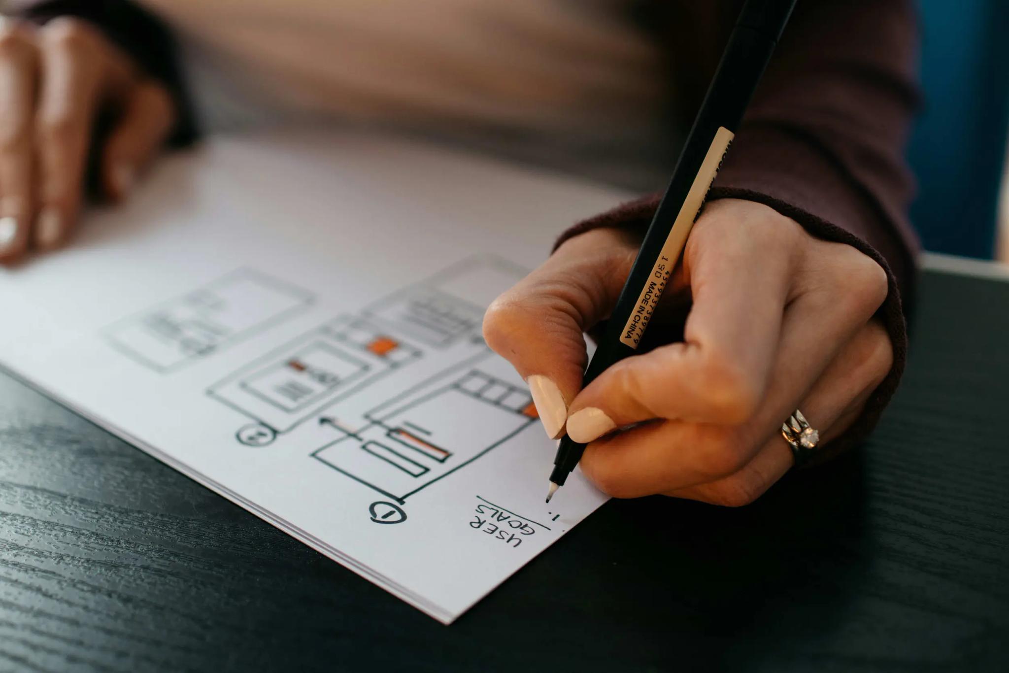 Hand drawing a diagram on paper with a pen