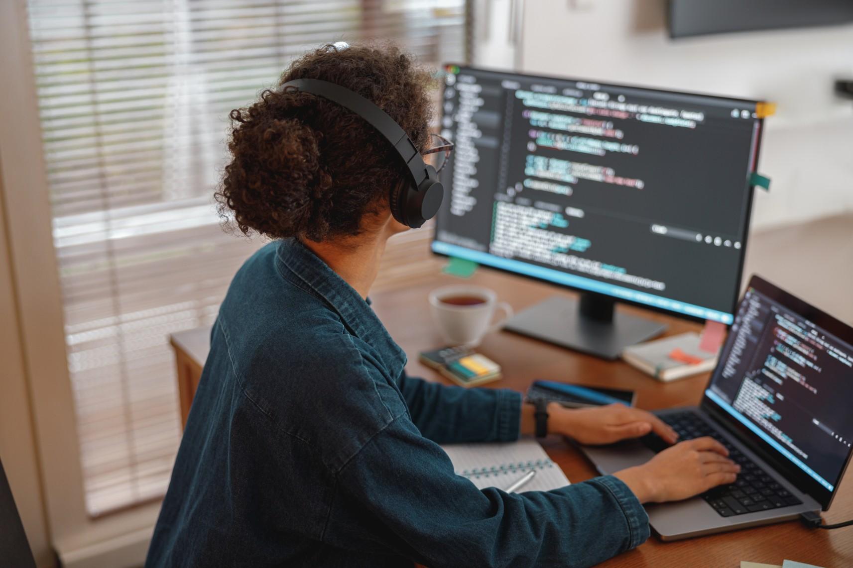 Person mit Kopfhörern programmiert am Computer.