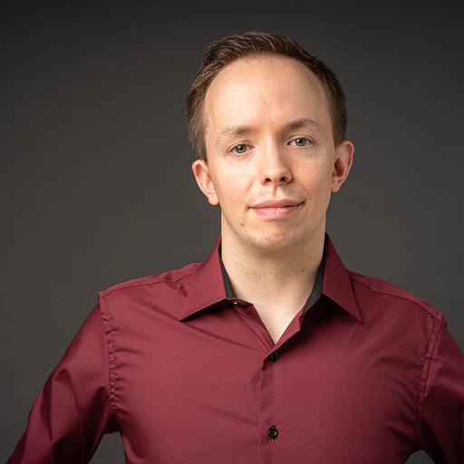 Portrait of a man in a red shirt against a dark background