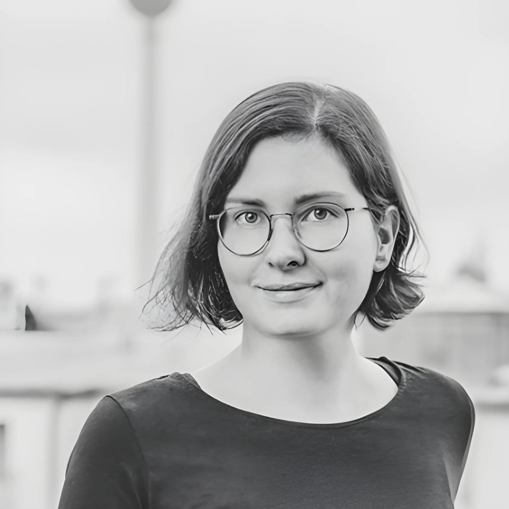 Portrait of a smiling person with glasses and short hair in black and white.