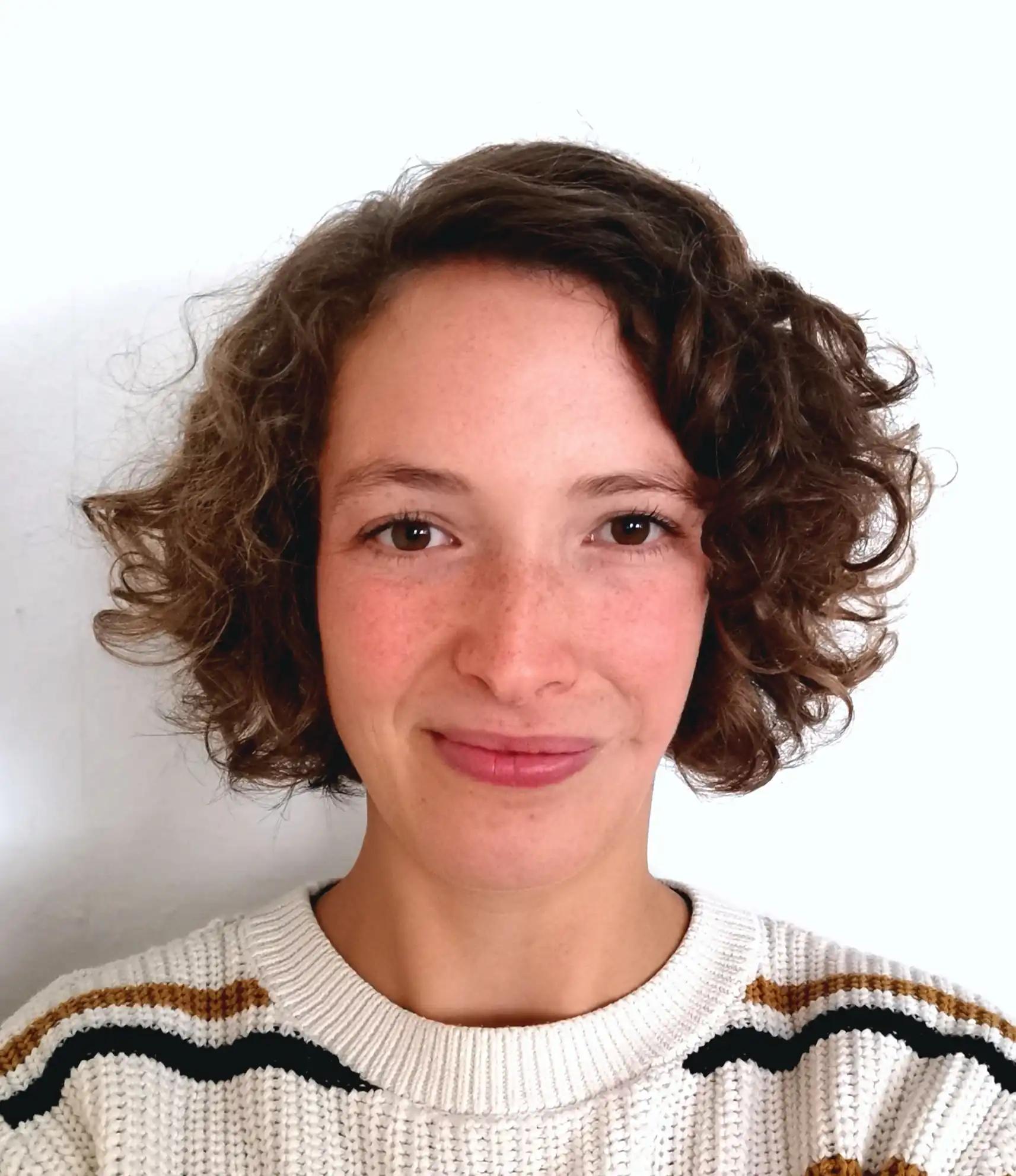 Portrait of a woman with curly hair wearing a sweater.