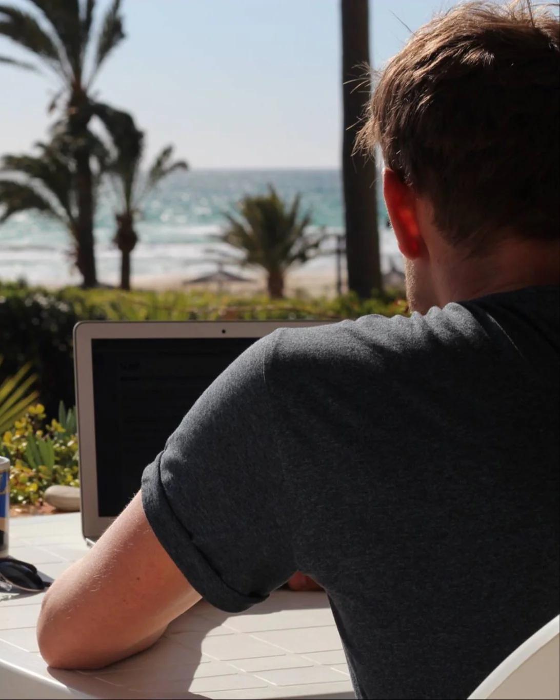 Person working on laptop with ocean view