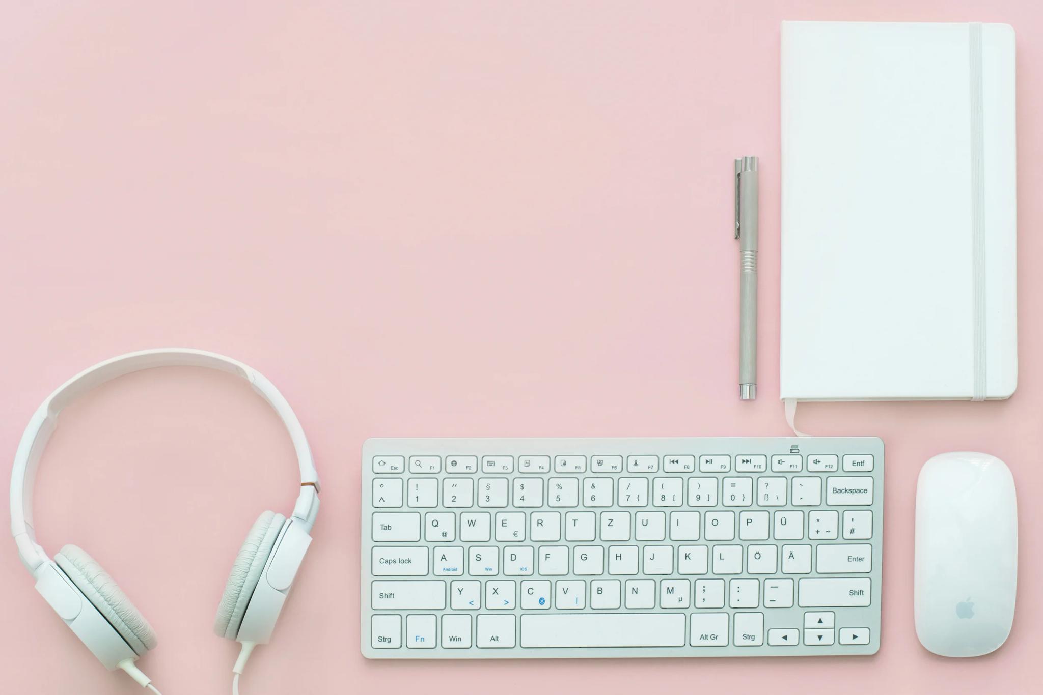 White computer accessories and notebook on pink background